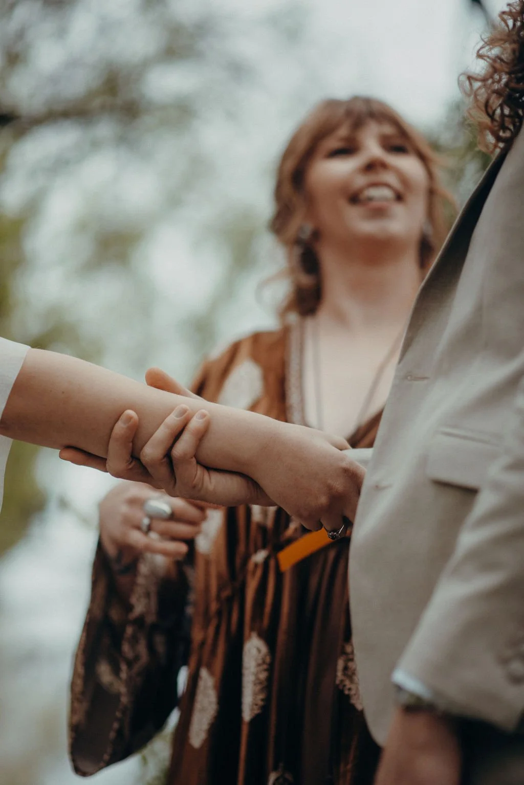 Cérémonie de mariage laïque handfasting en plein air dans les Hautes-Pyrénées : un couple marié s’enlace et se regarde tendrement, entouré d’arbres en fleurs, célébrée par Judith La Dame de Cœur