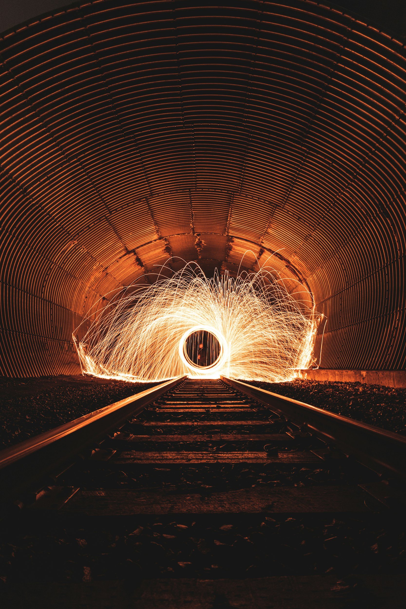 Light painting with sparks inside a train tunnel, viewed from the railroad tracks.