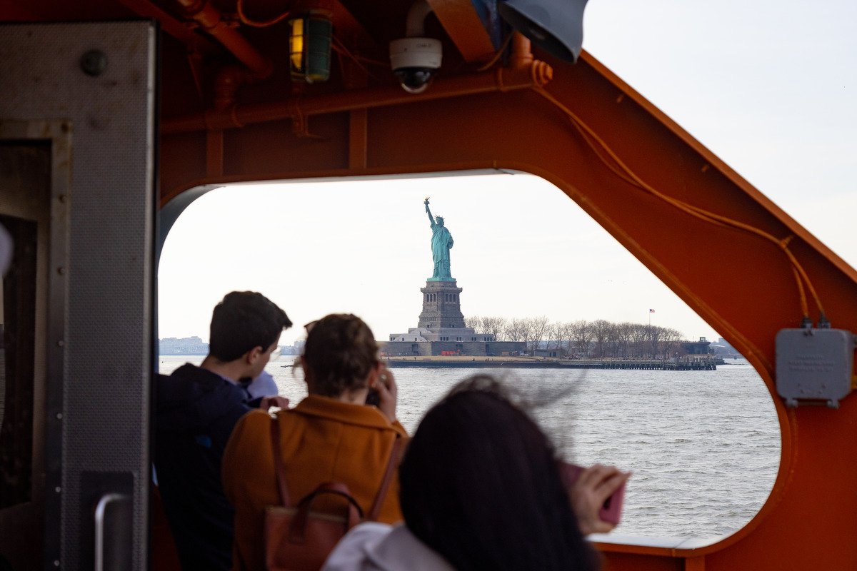 Staten Island Ferry passengers look at the Statue of Liberty.