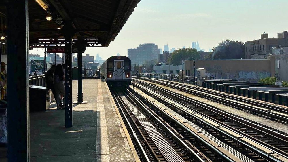 A subway train approaches an outdoor station.