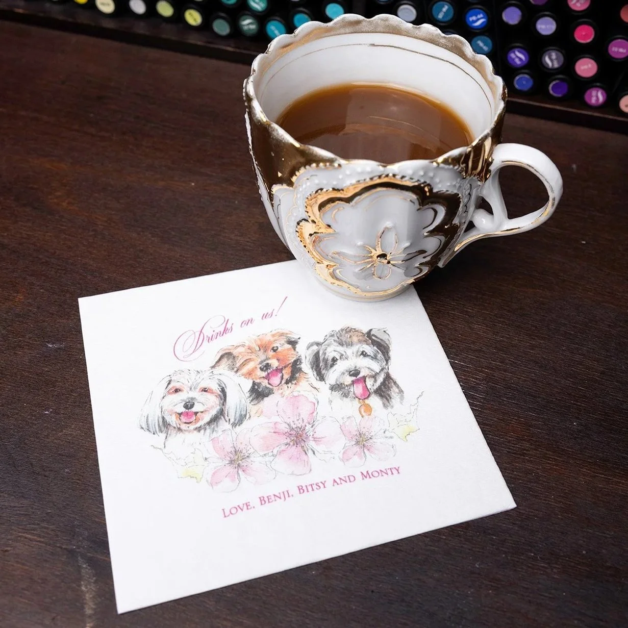 Custom illustrated cocktail napkin featuring bespoke pet portraits by Vogue Vignette, showing three dogs with florals and personalized wedding bar signage text