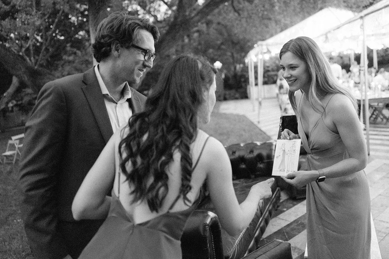 Wedding guest receiving her bespoke live portrait illustration from a Vogue Vignette artist at an outdoor wedding reception, captured in the moment of reveal.