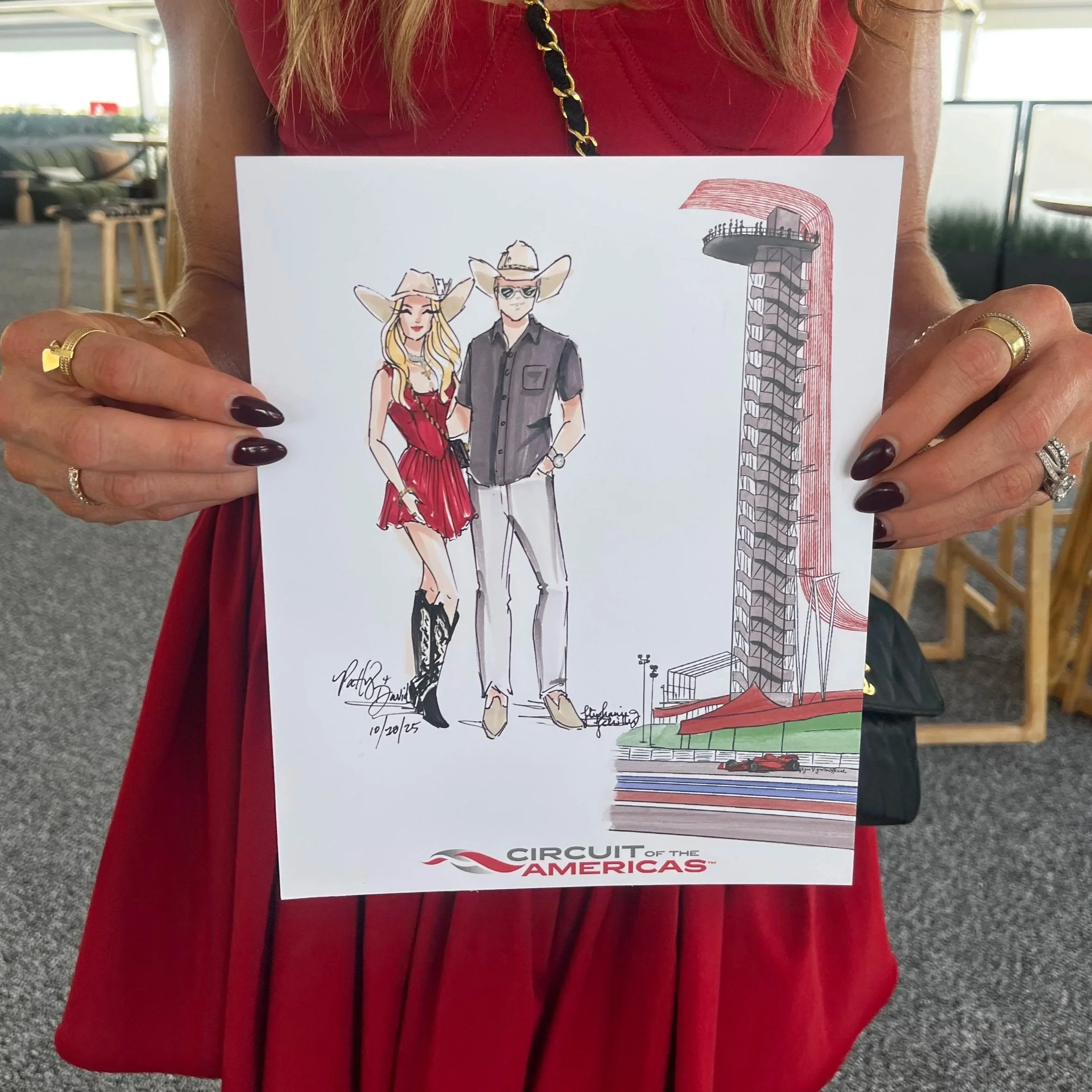 Stylish woman in red dress and cowboy hat holding her Vogue Vignette custom illustration by Stephanie J. Schiller at the F1 Grand Prix in Austin Tx