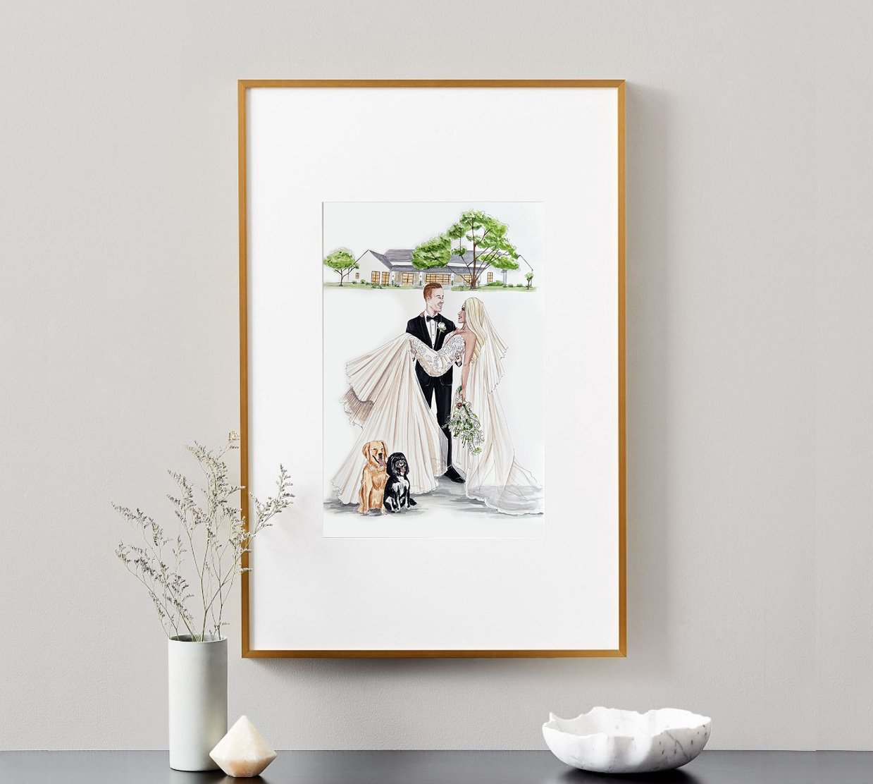 Bespoke Vogue Vignette Signature Newlywed Portrait displayed in a gold frame, featuring a watercolor illustration of a bride and groom with their two dogs and wedding venue painted in the background.