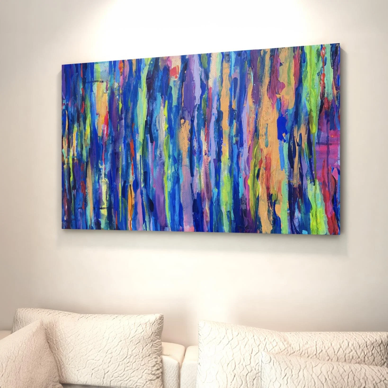 “Shimmer” mounted above a plush white couch in a softly lit interior, emphasizing its rich saturation and dynamic flow of cascading colors.