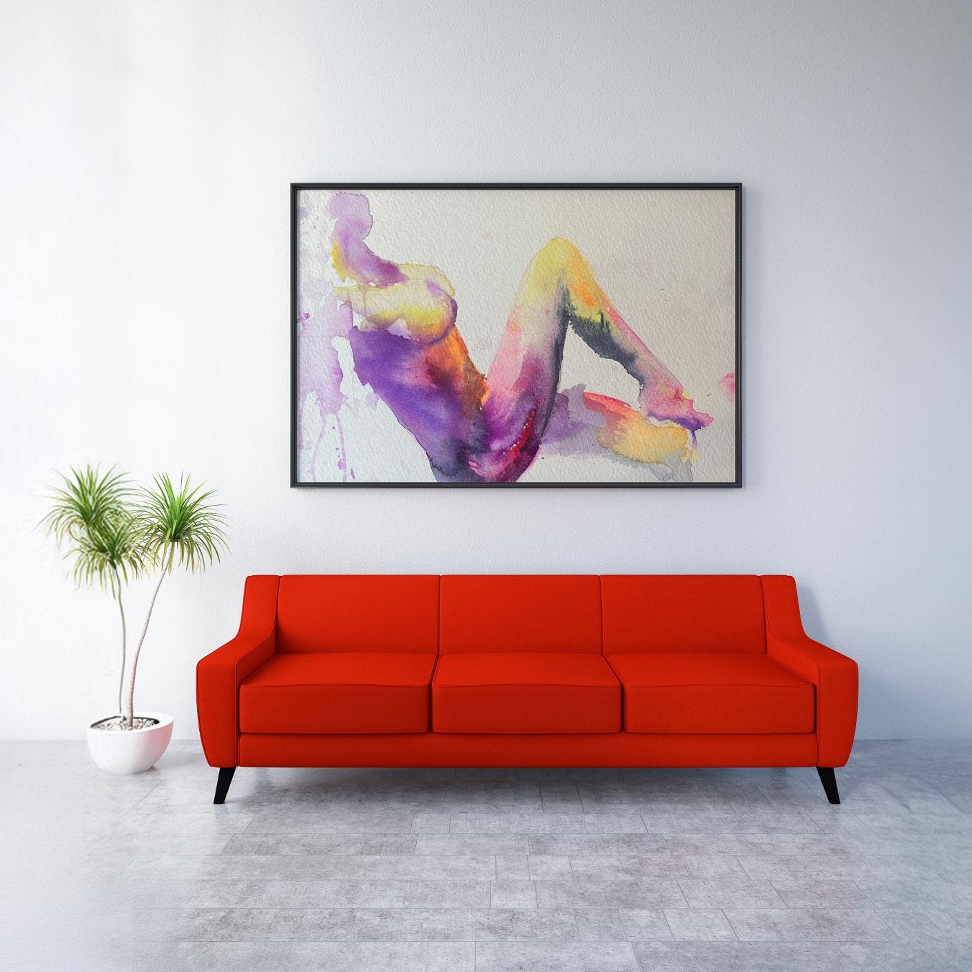Framed nude watercolor artwork displayed in a minimal interior with a red couch and small potted plant, emphasizing contrast and bold color presence.