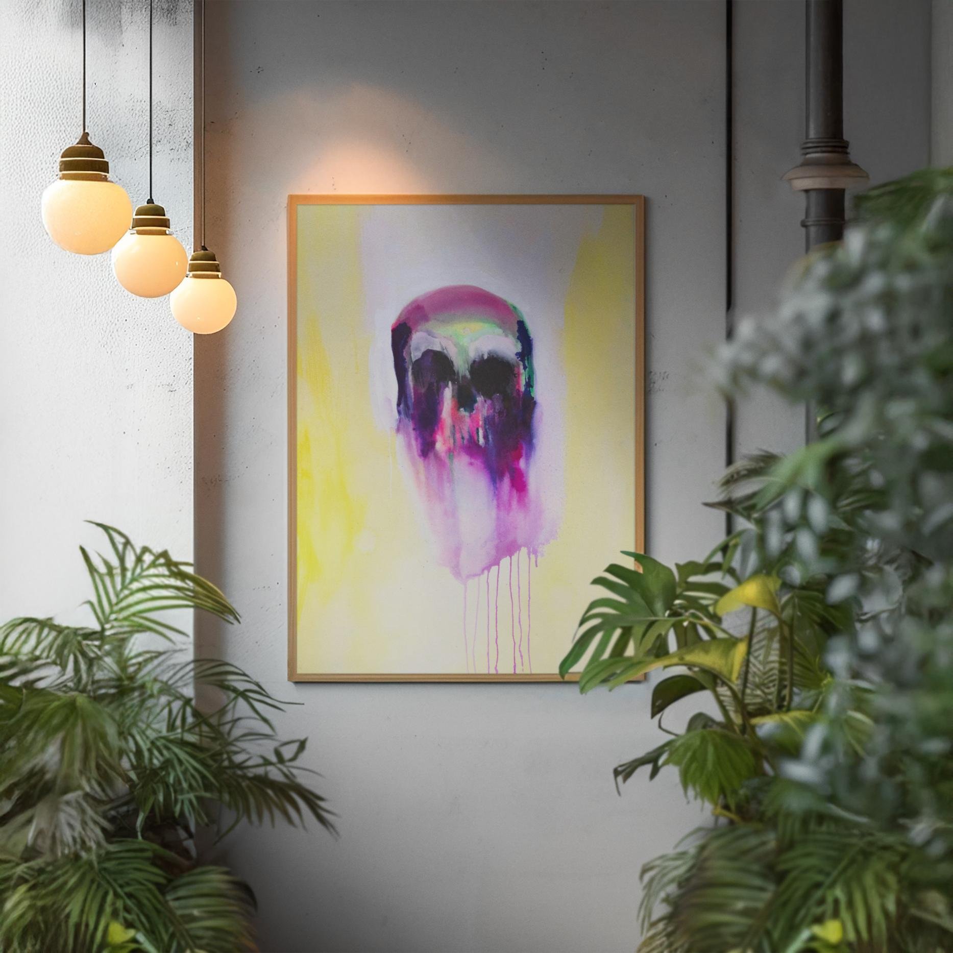 Abstract skull painting framed in gold, mounted near warm pendant lights and surrounded by leafy plants, creating a cozy, artistic ambiance.