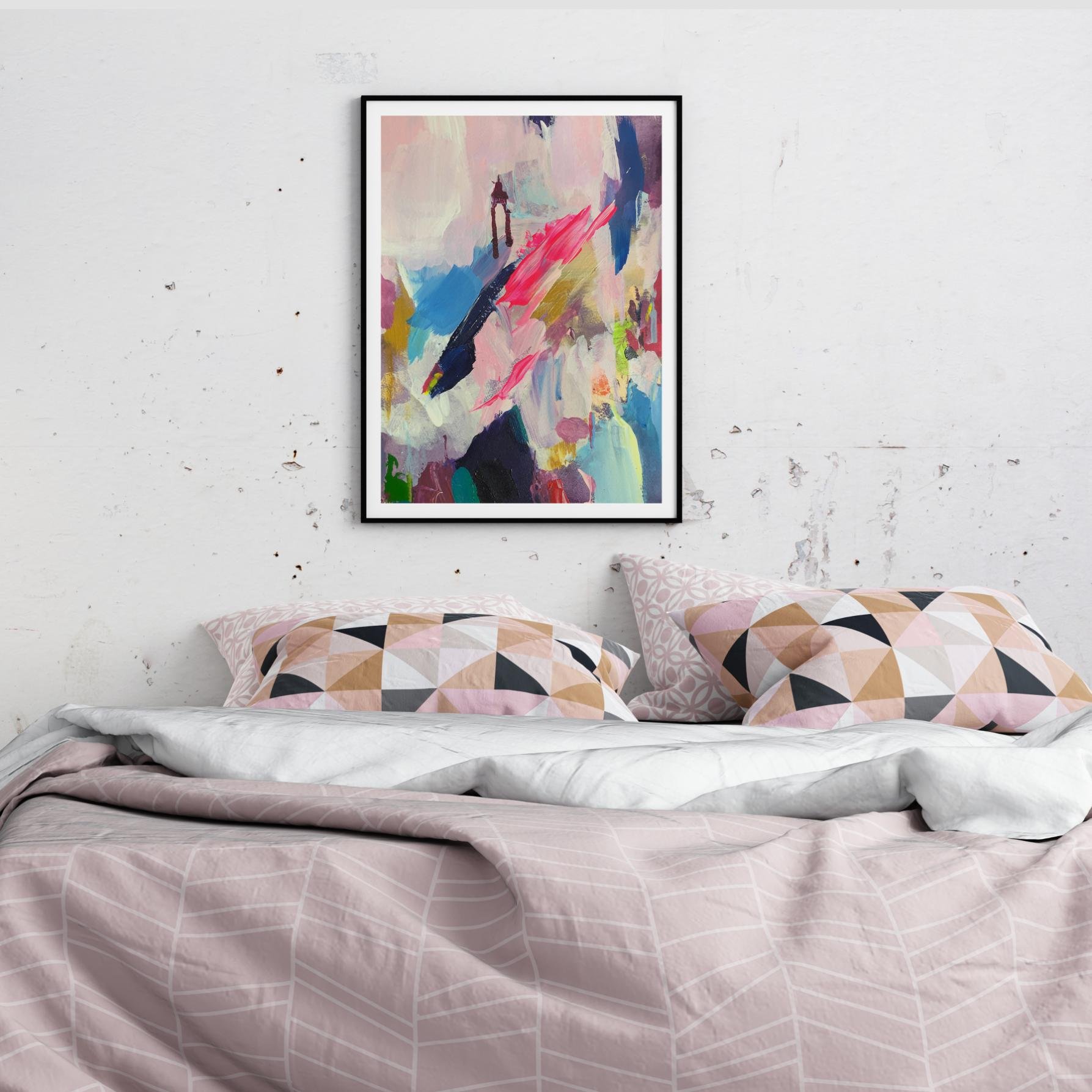Abstract artwork with vivid strokes of pink, blue, and gold framed above a bed with patterned pillows and pink bedding in a rustic, textured room.