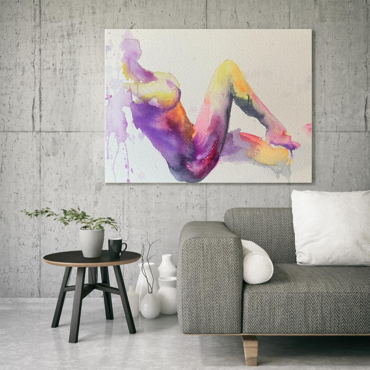 Horizontal nude watercolor art piece displayed in a modern living room with concrete walls, showing colorful purples, yellows, and pinks.