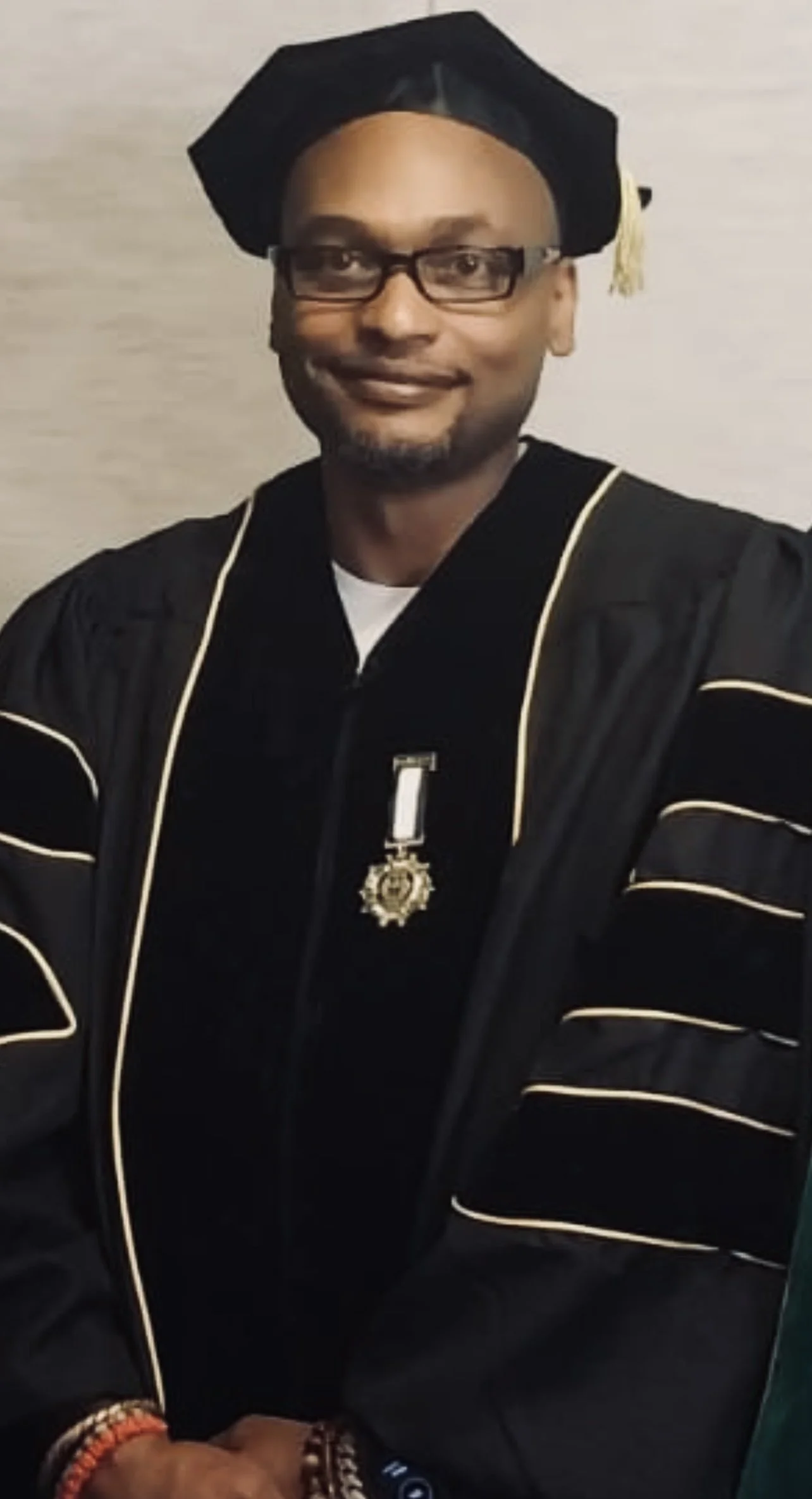 Formal academic portrait taken following the conferral of the Doctor of Philosophy (Ph.D.) in Theology, reflecting a lifelong commitment to scholarship, traditional wisdom, and the preservation of African spiritual heritage.