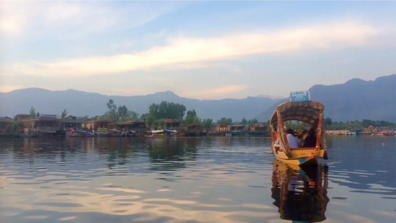 Lake Srinigar at dusk, himalayas in the background and a golden boat in the foreground, crystal waters.