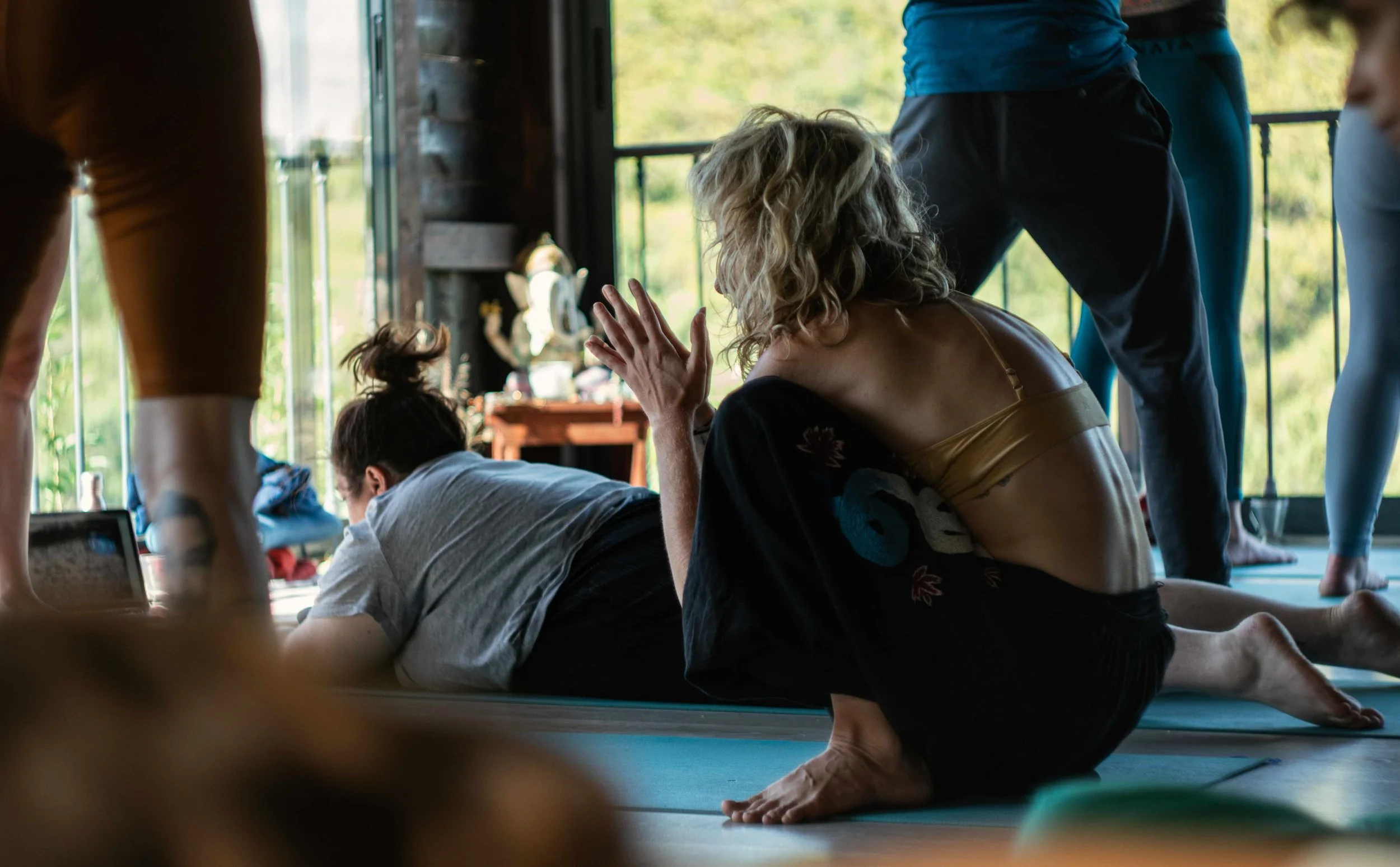 A women crouched on the floor in movement practice, in a deep squat, her hands in prayer.