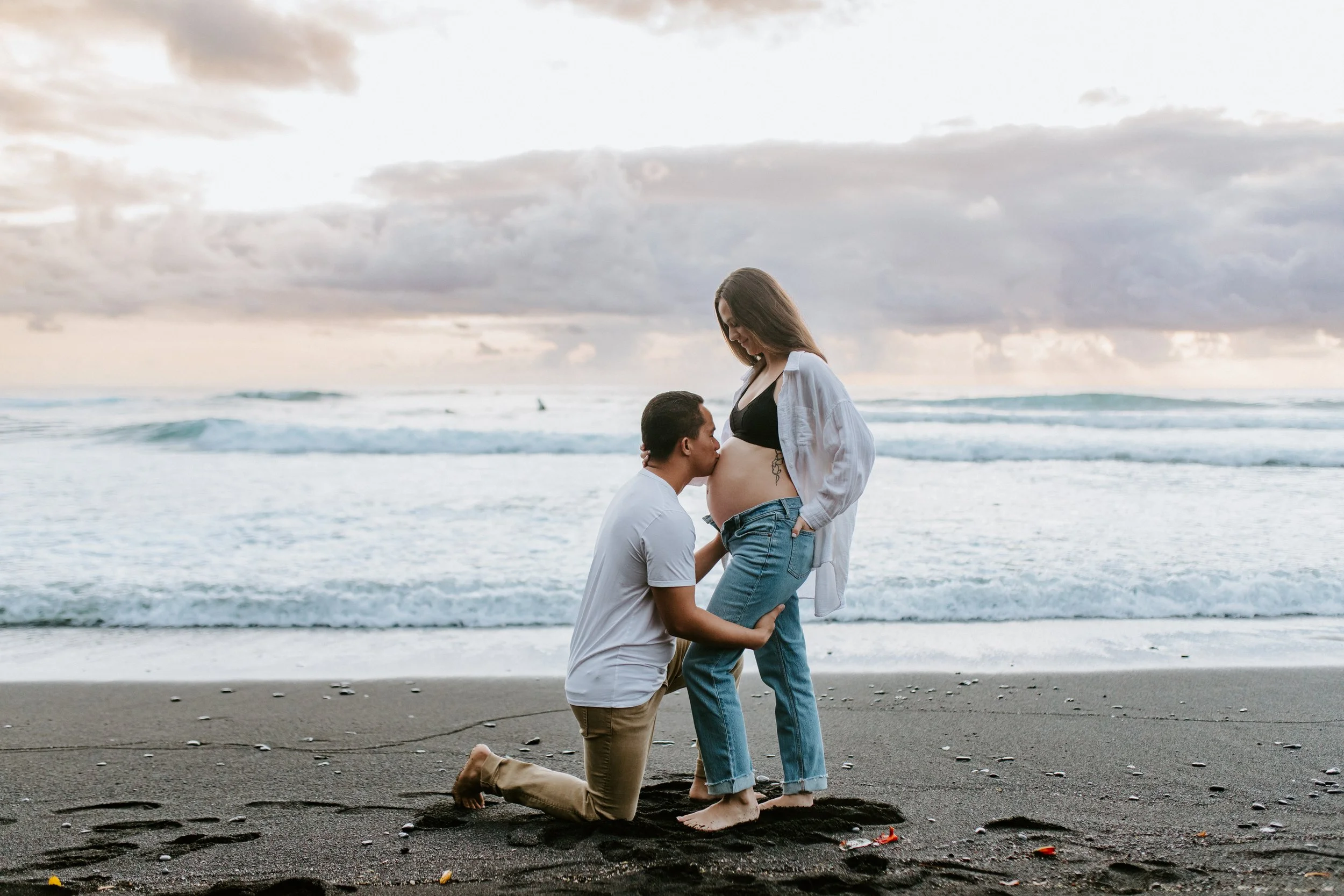 Husband kisses belly on the beach in Hawaii as they await their son.
