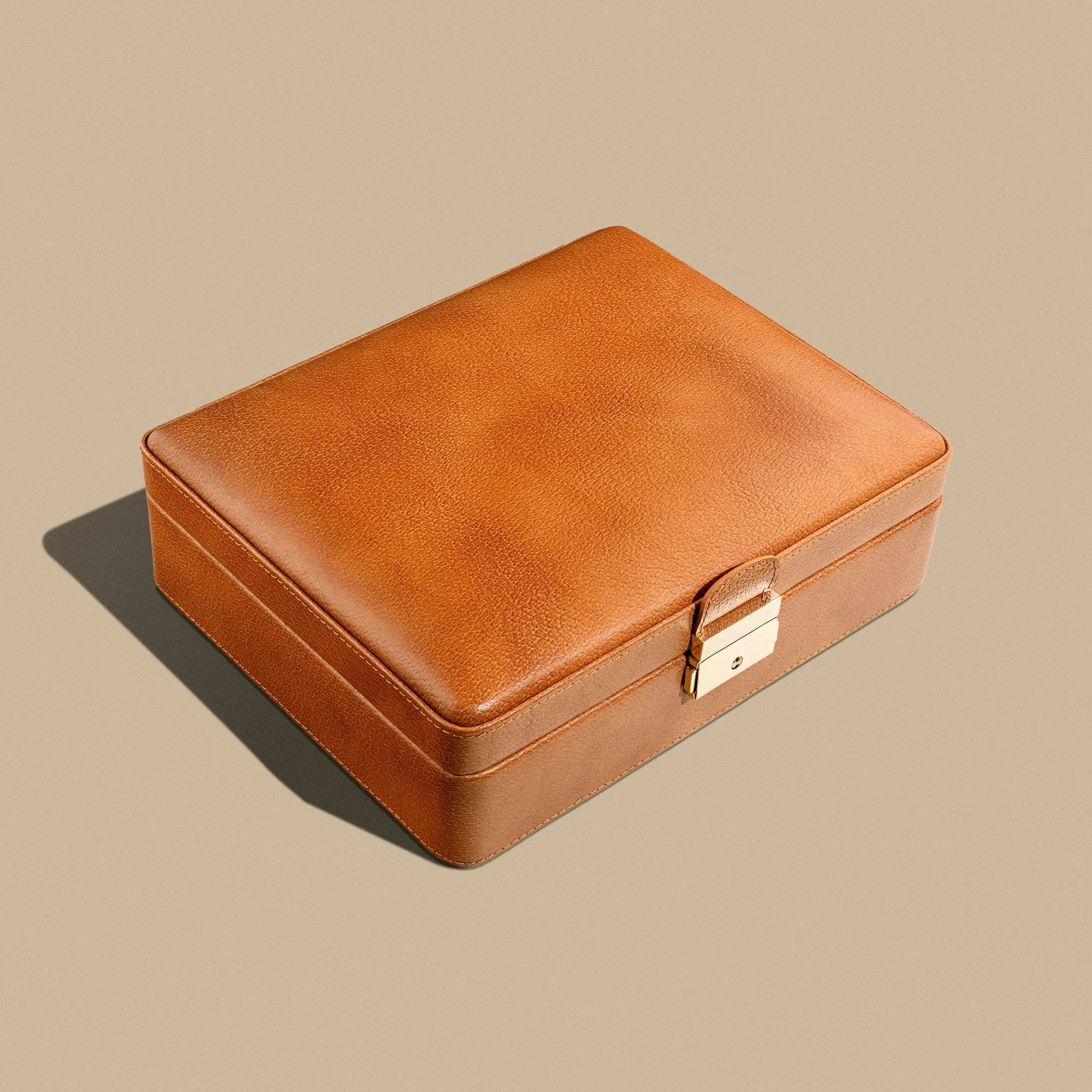 Closed brown leather box with a metal latch on a beige background.