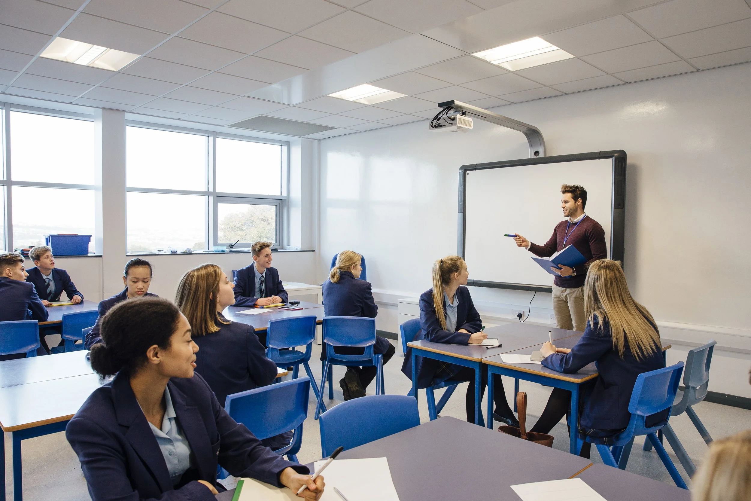Male teacher teaches a group of teenagers in a classroom