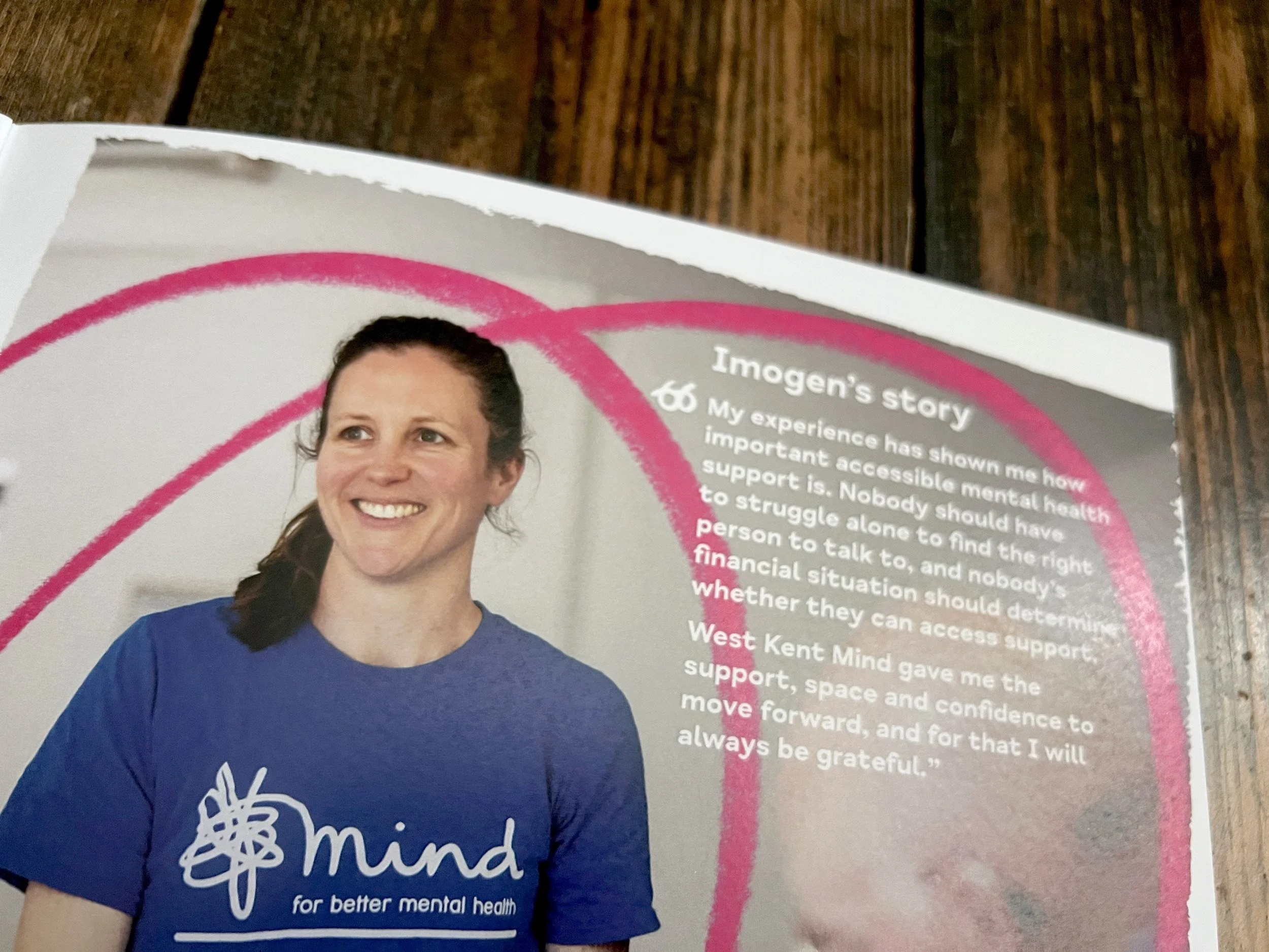 A lady smiling and wearing a Mind t-shirt, the image has a pink squiggle on it with a panel of text titled 'Imogen's Story'.