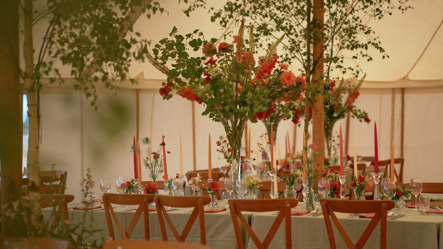 Party tables in marquee decorated with flowers by Kate Gordon Lennox