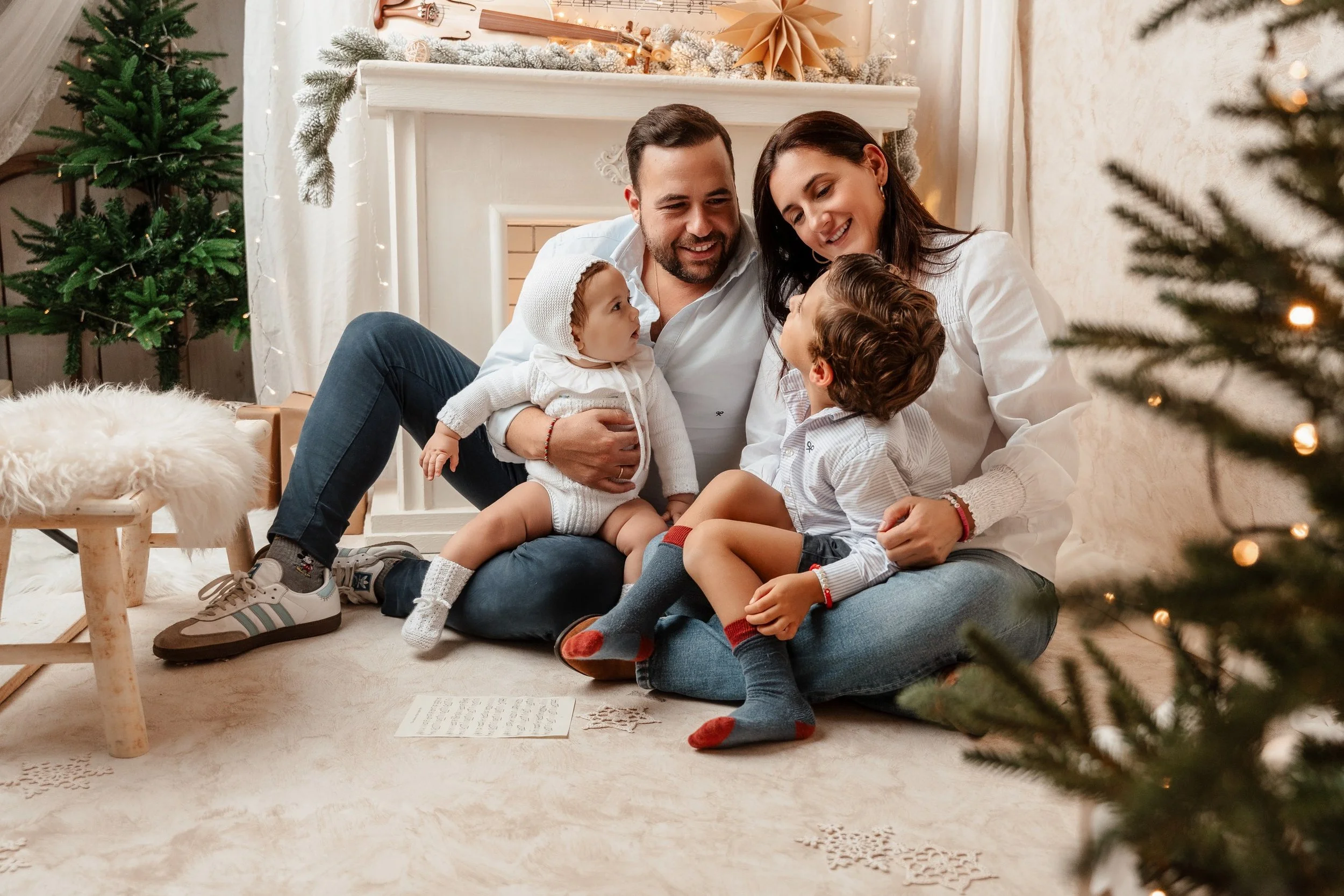 Una familia disfrutando de una reunión navideña en un salón decorado con árboles de Navidad y adornos festivos.