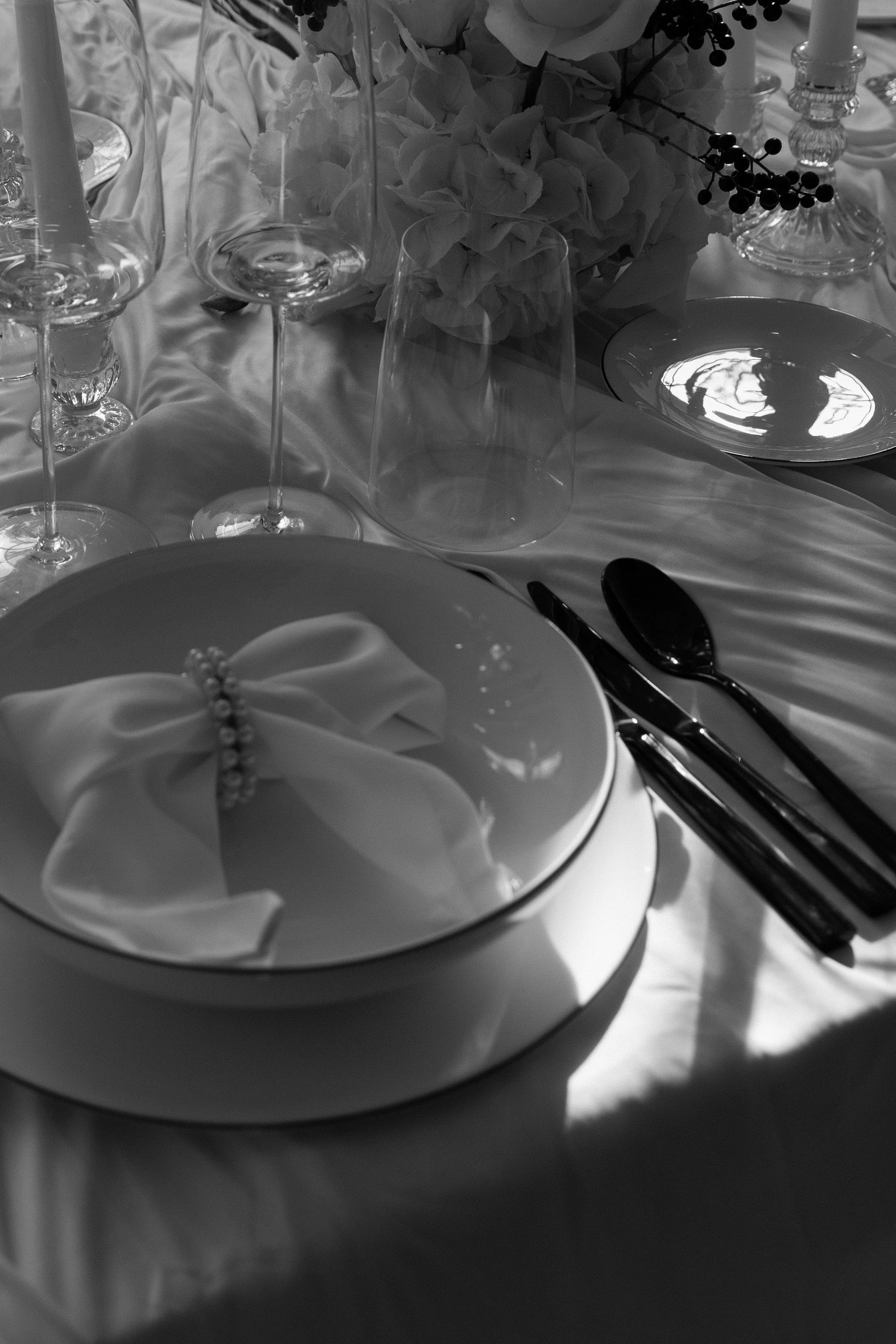 Ein eleganter gedeckter Tisch mit Geschirr, Gläsern, Silbern, einer Blumenarrangement und Dekorationen für eine formelle Veranstaltung.