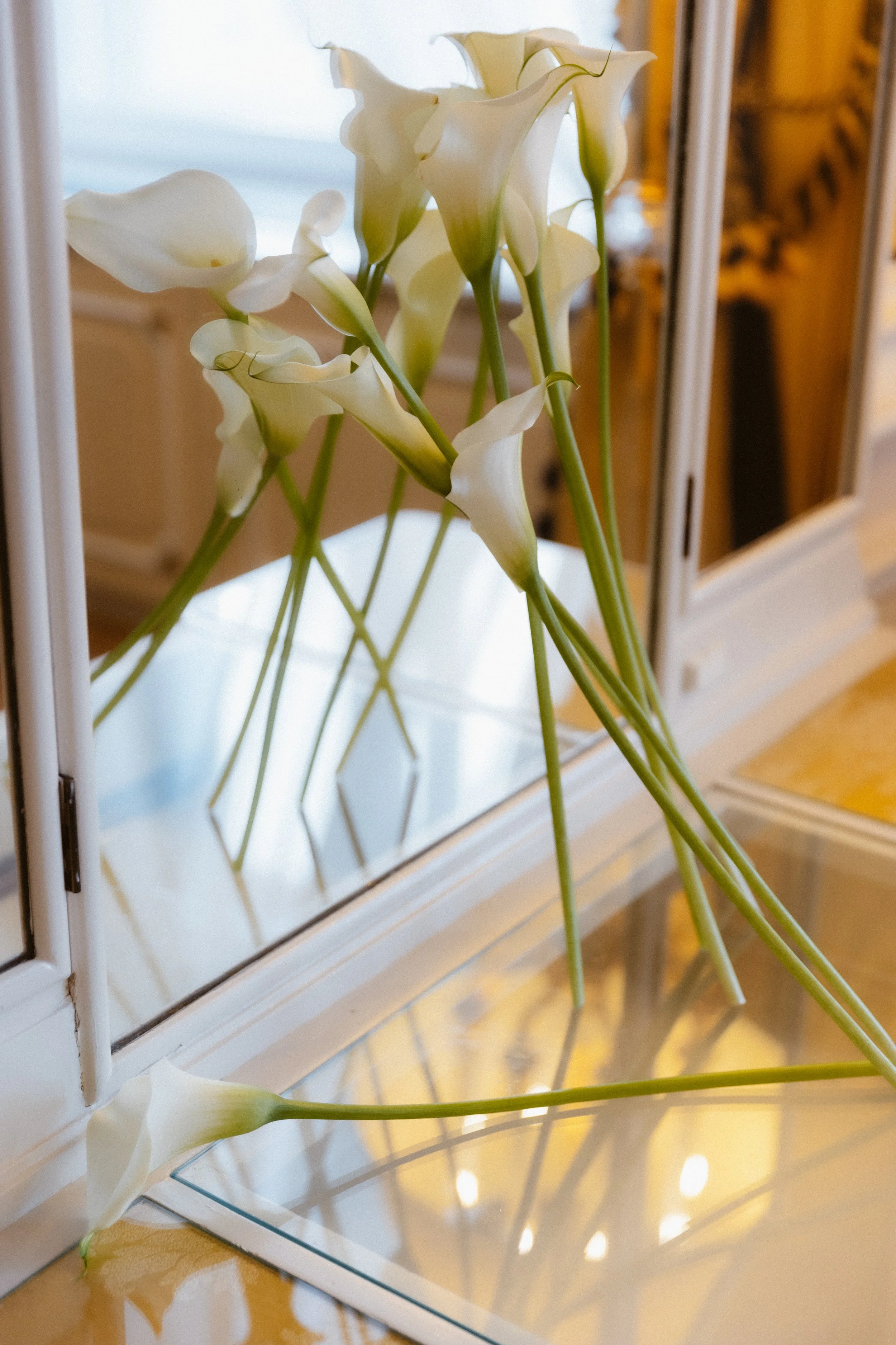 Weiße Calla-Lilien in einem Spiegelrahmen