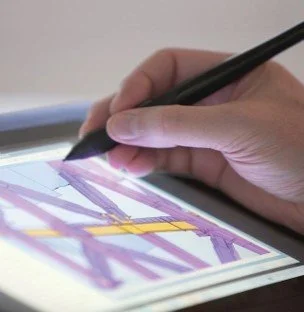 Nahaufnahme einer Hand, die mit einem digitalen Eingabestift eine technische 3D-Struktur auf einem Tablet bearbeitet. Die Szene symbolisiert die Schnittstelle zwischen klassischer Ingenieursplanung und moderner BIM-Methodik.