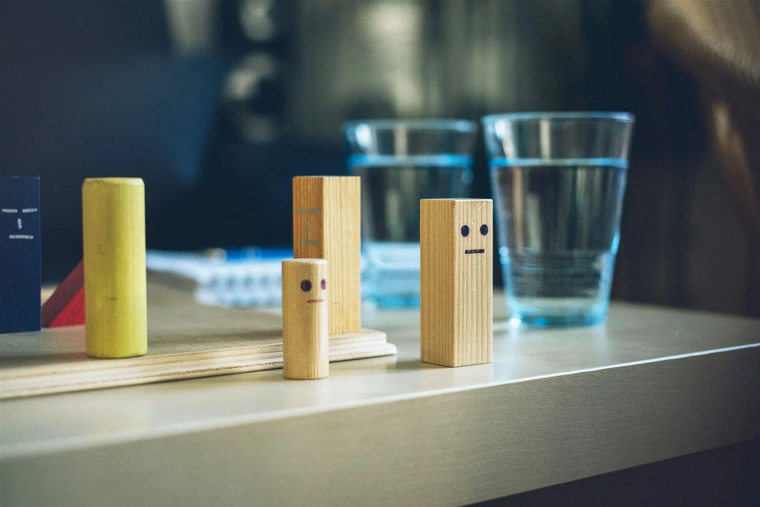 Holzbausteine mit Gesichtern repräsentieren die unterschiedlichen Parteien in einer Mobbing Situation bei Business Coach Silvia Schäfer