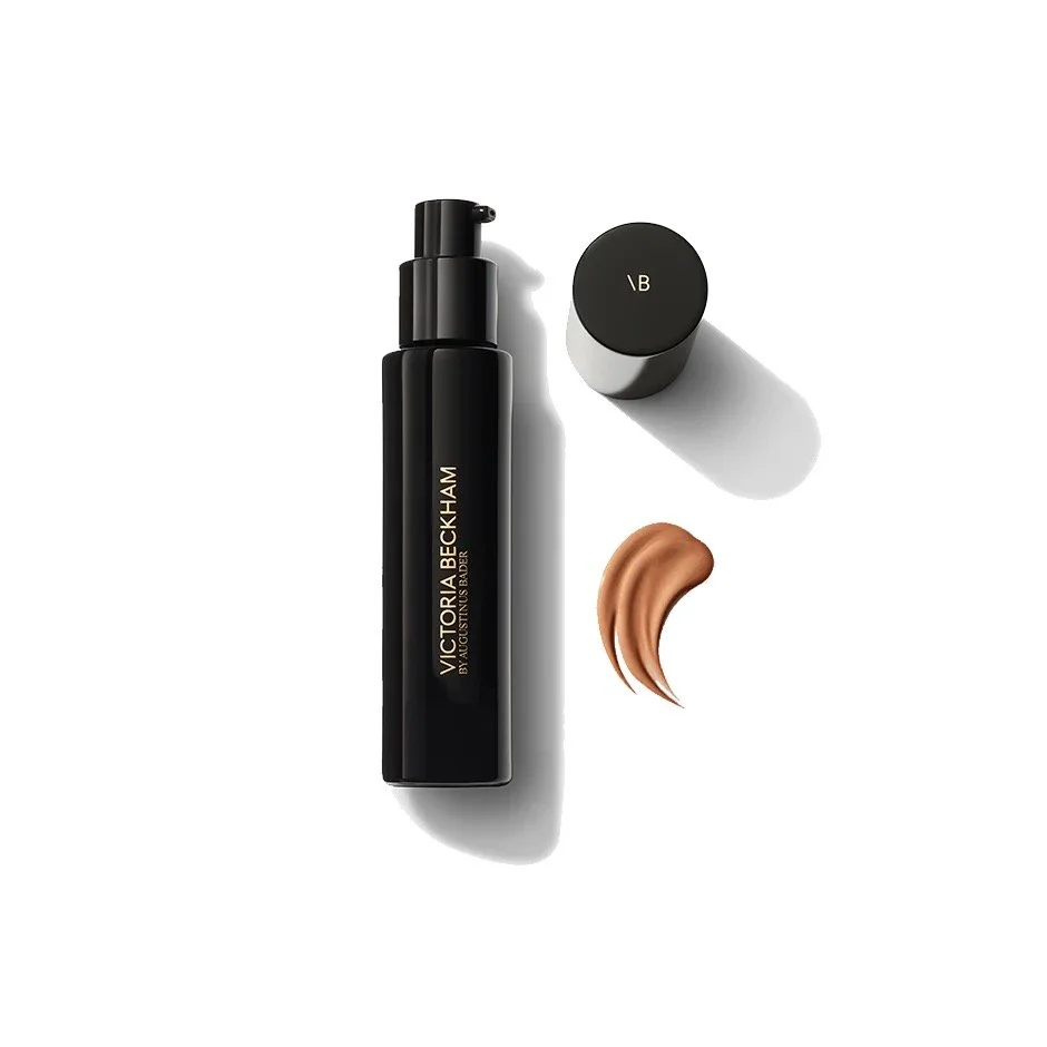 Black bottle of Victoria Beckham brush mousse with a beige swatch of product and a black cap