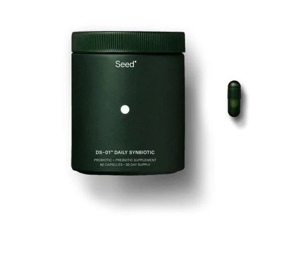 A green container of Seed Daily Synbiotic probiotic capsules next to a single capsule on a white background.