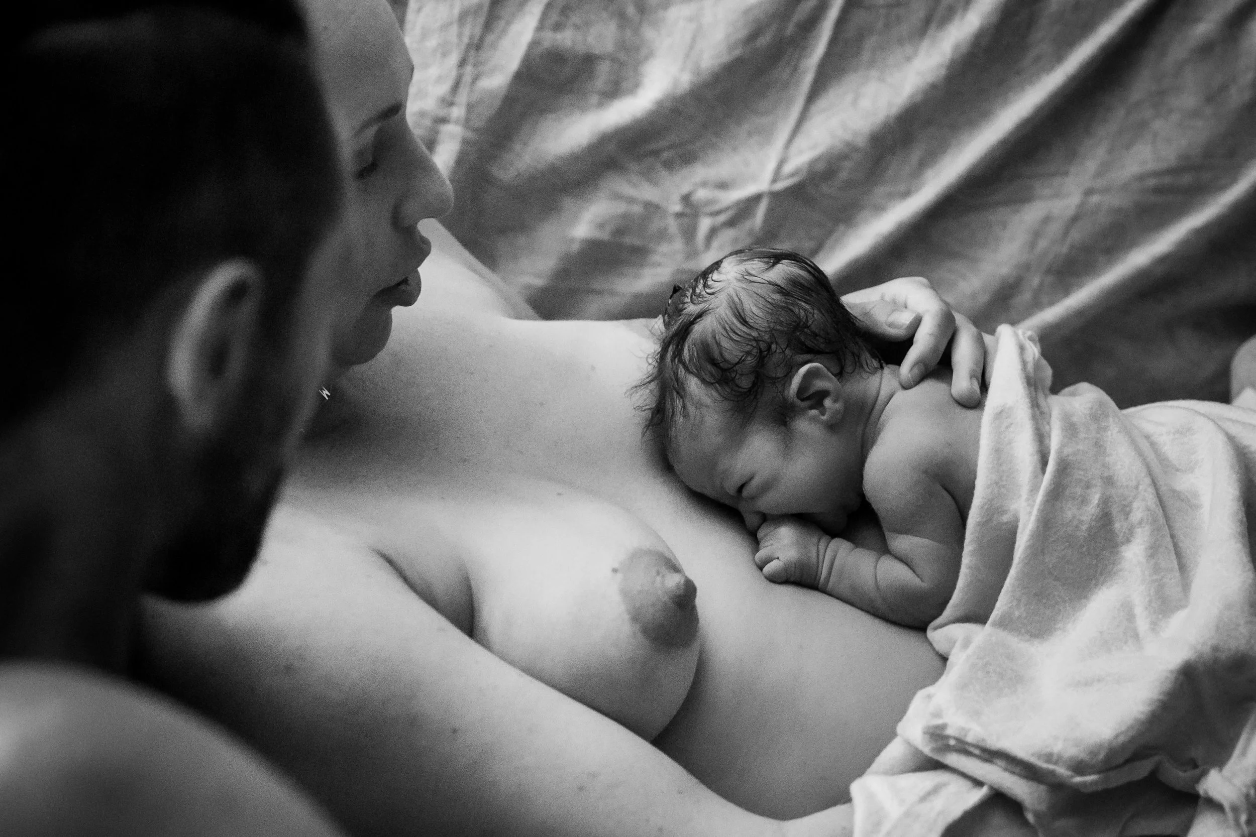 newborn baby crawling up mom's chest during golden hour, home birth with doula and midwife, ventura birth photography