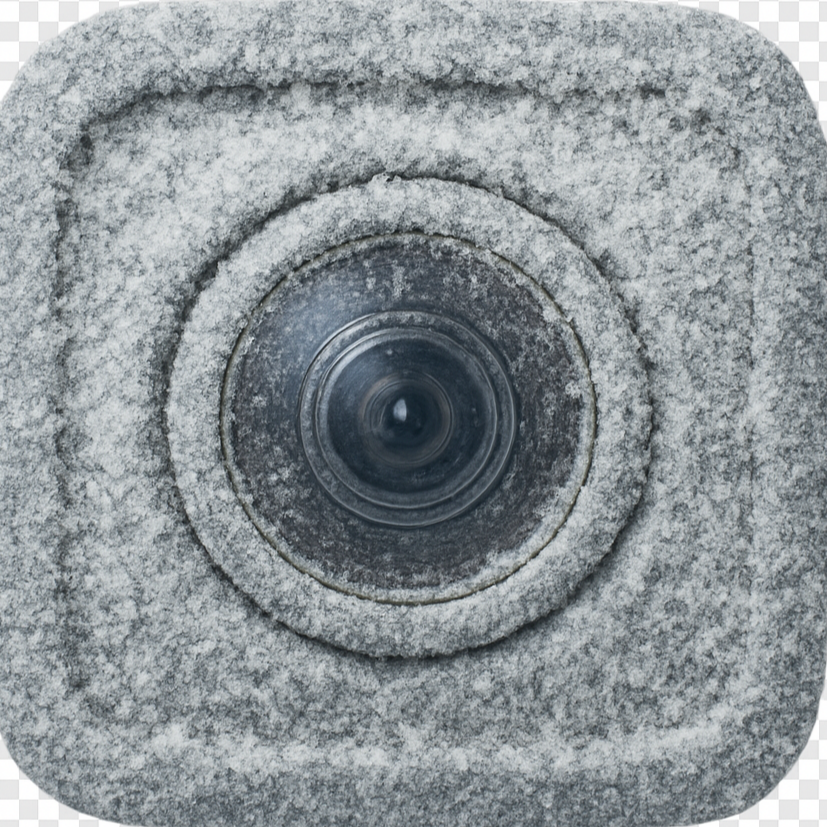 Close-up of a surveillance camera embedded in a snow-covered concrete wall.