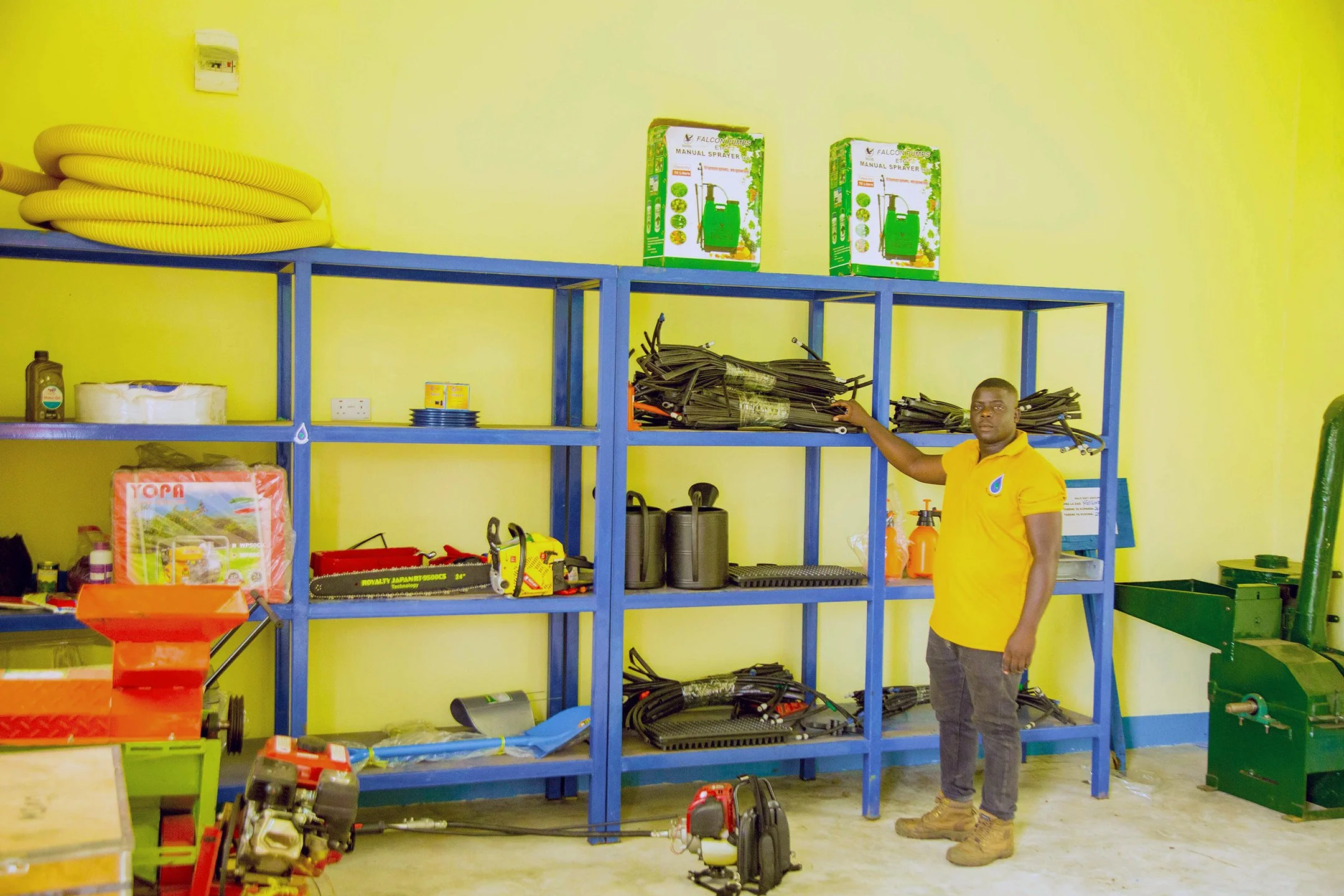 A man in a yellow shirt standing in a store with various tools and supplies.