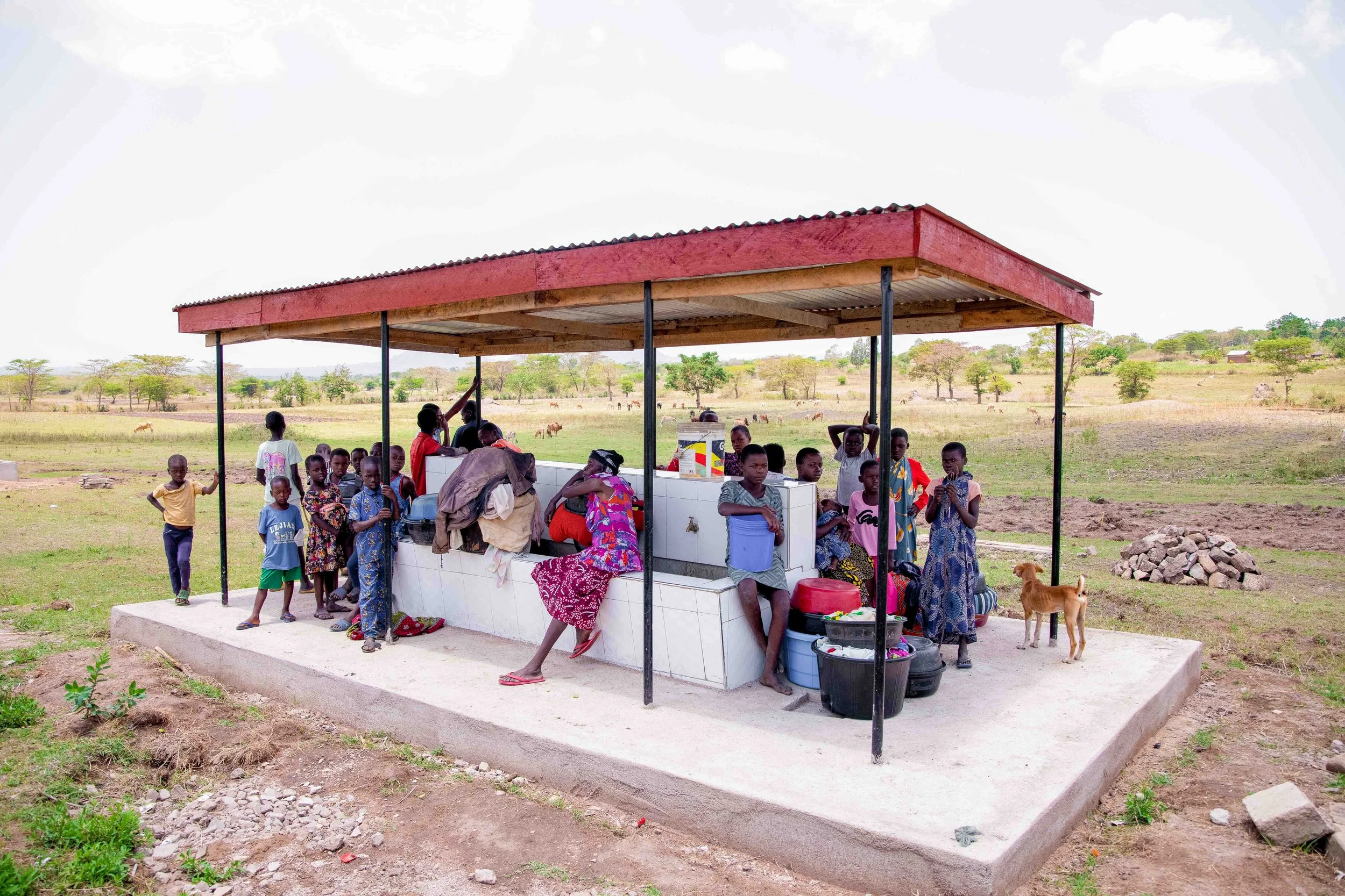 Children and women gathered around a water station.