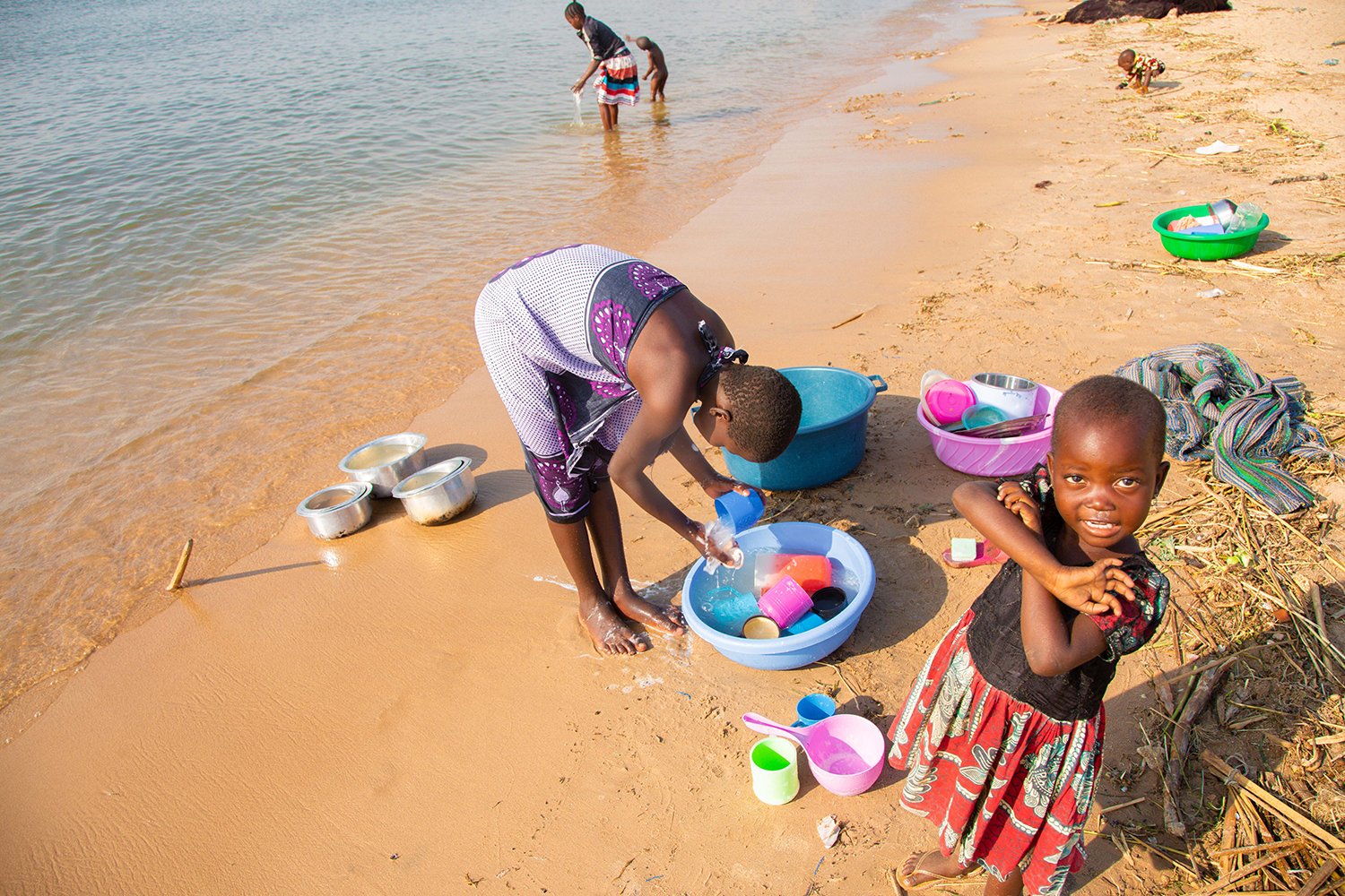 Mother and children collecting water at shoreline