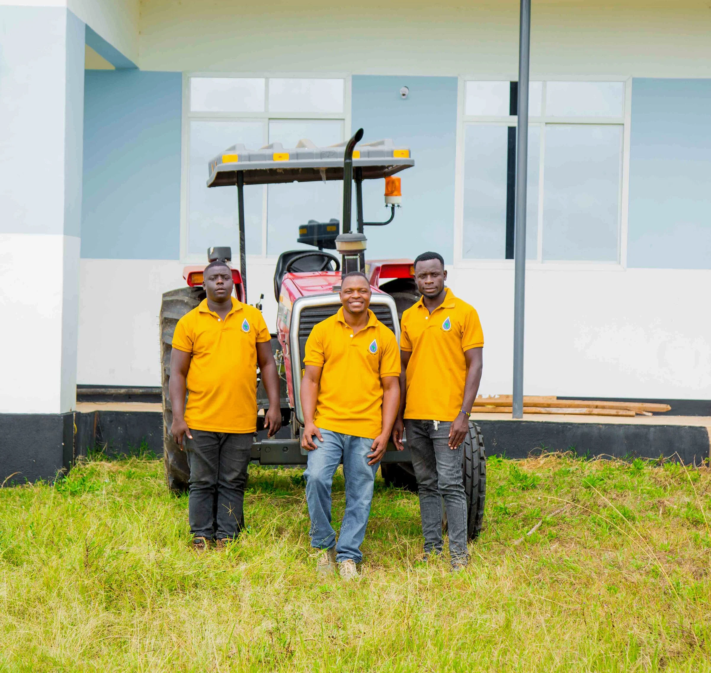 Four young men on MSG team standing in front of a tractor and building under construction.