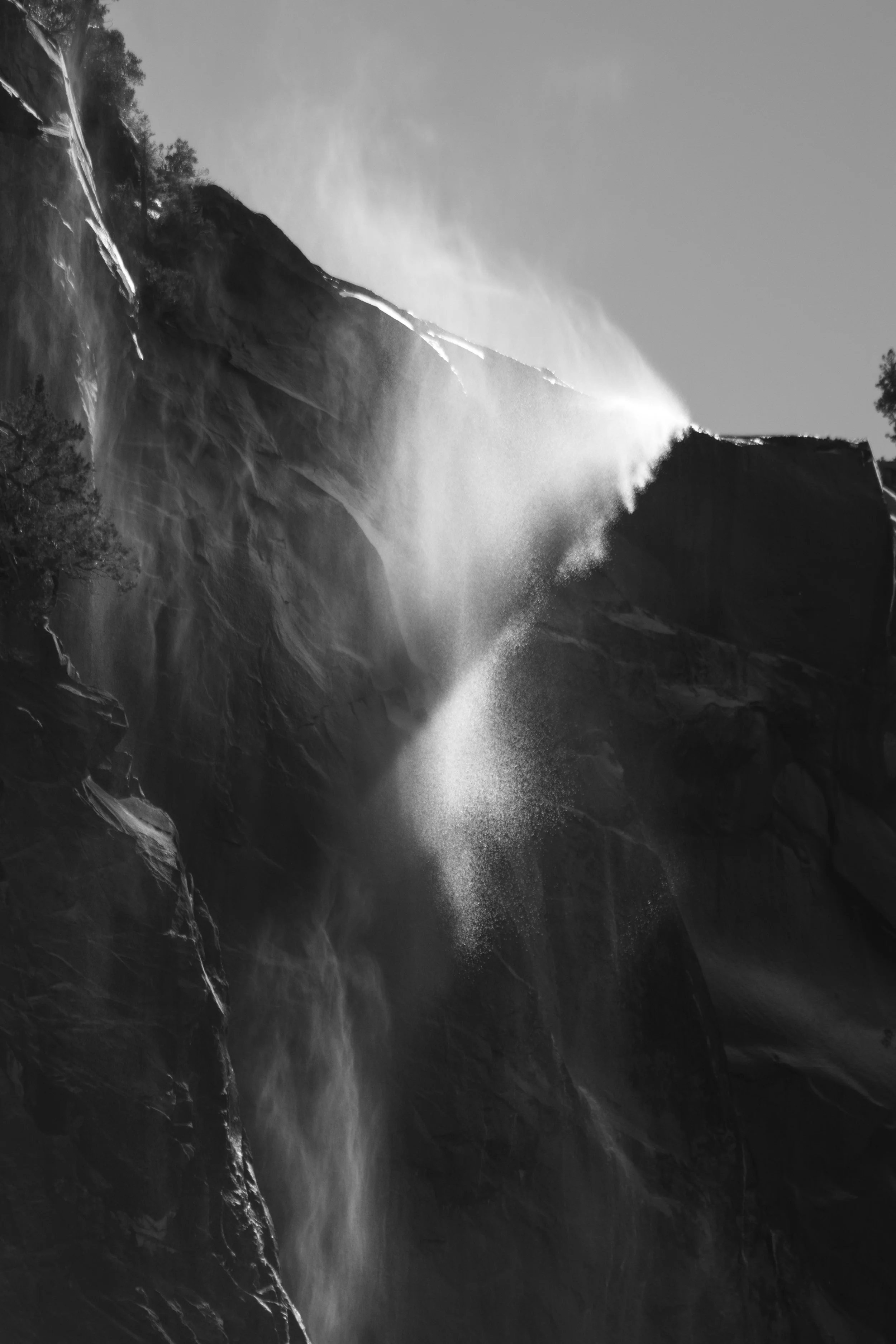Black and white photograph of a waterfall cascading down a rugged cliffside with mist rising at the top.