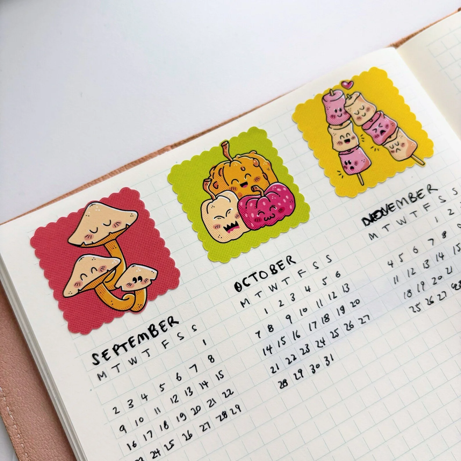 Bullet journal open to September, October, and November pages with seasonal stickers marking each month
