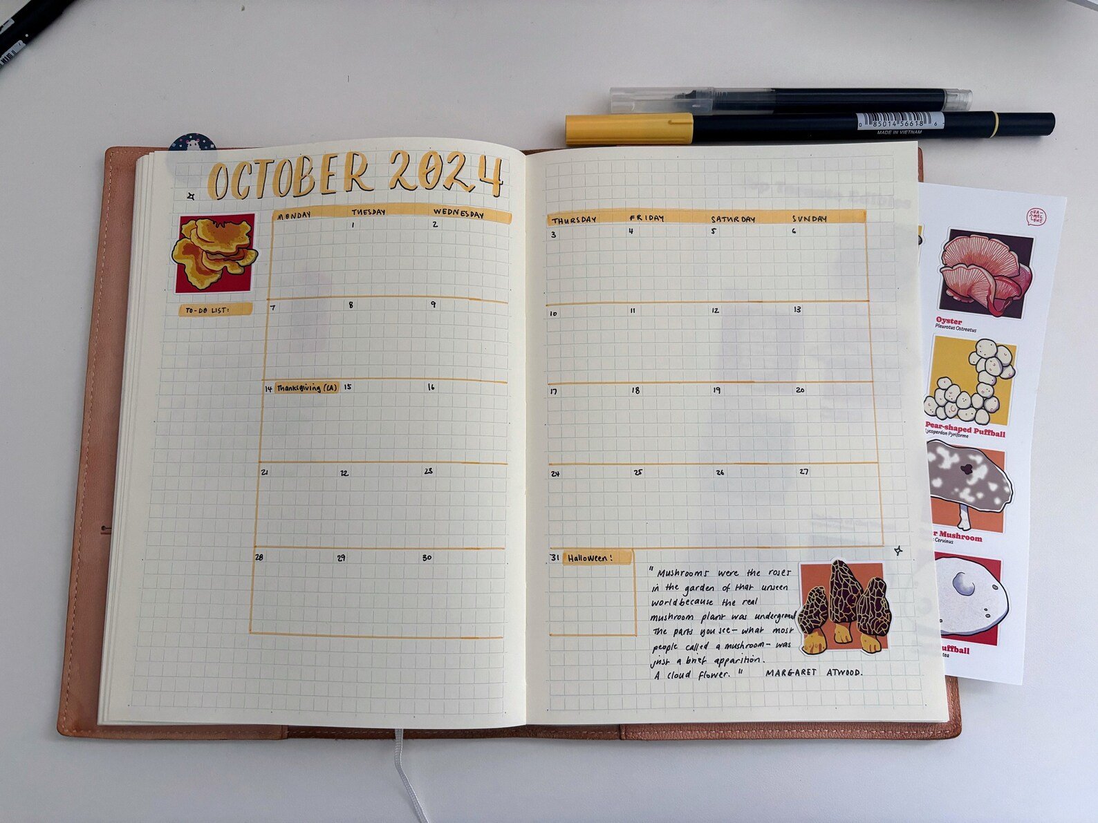 Open bullet journal for October 2024 featuring hand-drawn mushroom illustrations and a Margaret Atwood quote