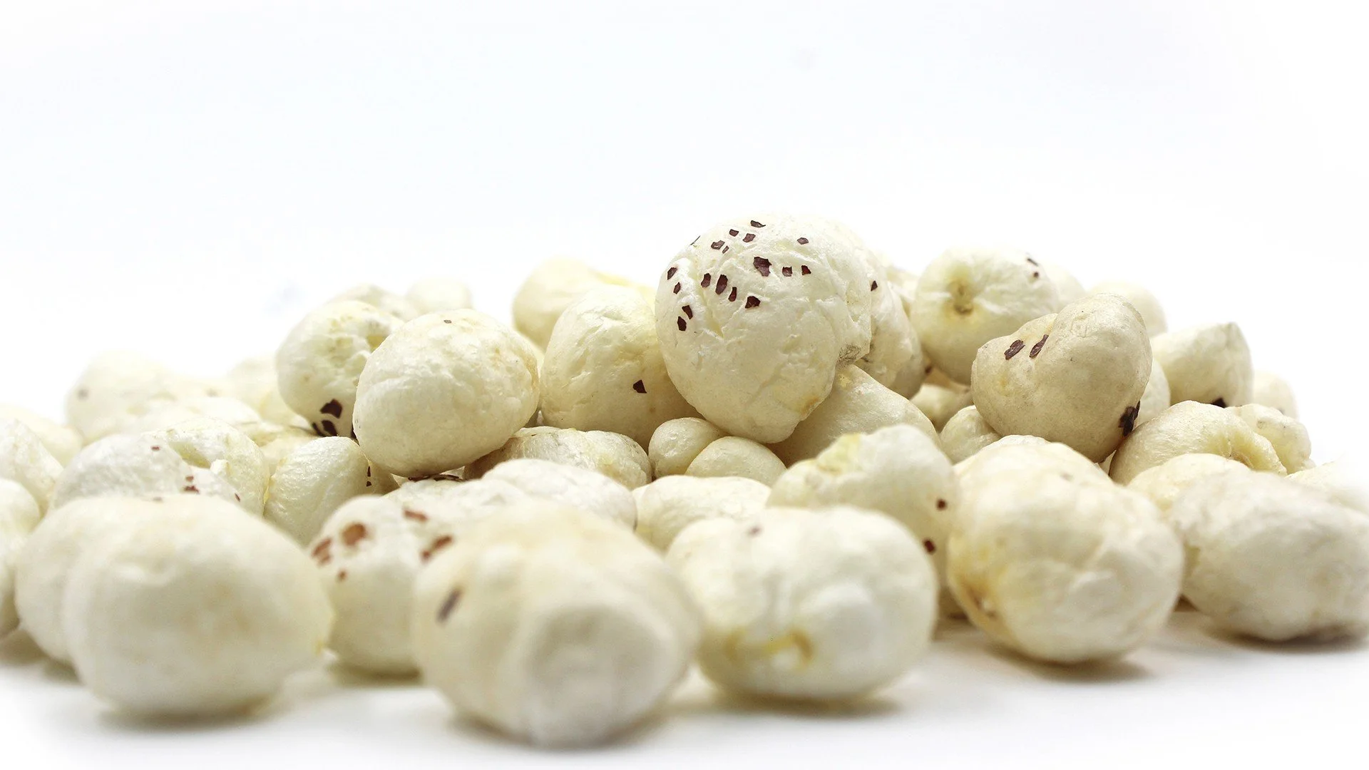 Heap of white chocolate-covered popcorn with small dark chocolate pieces on a white background