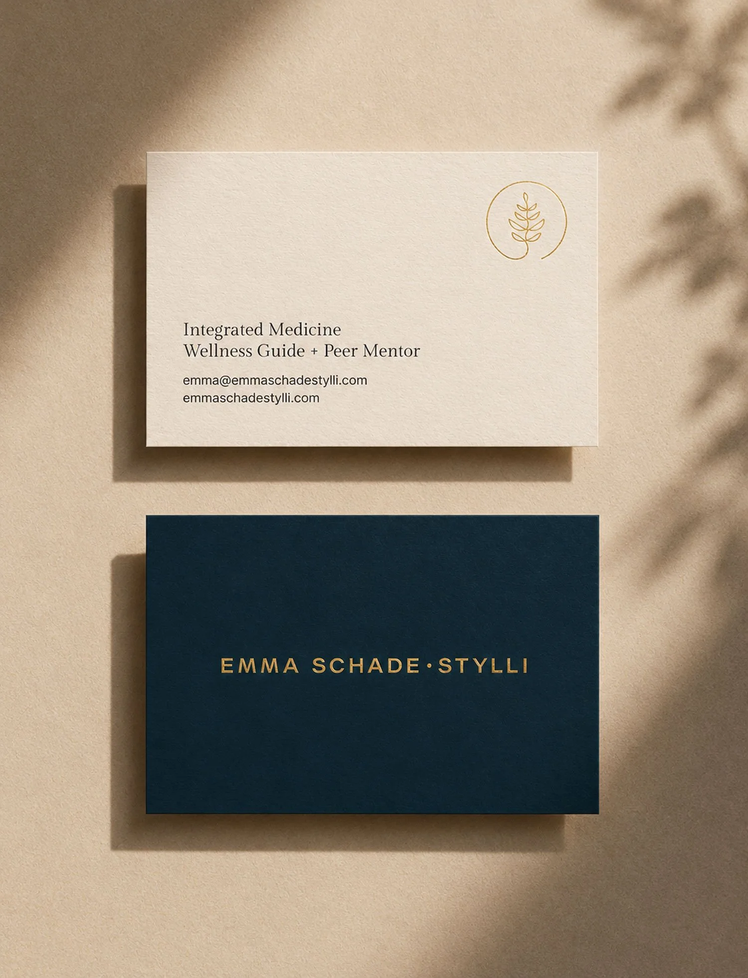 Gold foil business card mockup for Emma Schade-Stylli, featuring ivory and deep teal cards on a warm textured background with soft shadows
