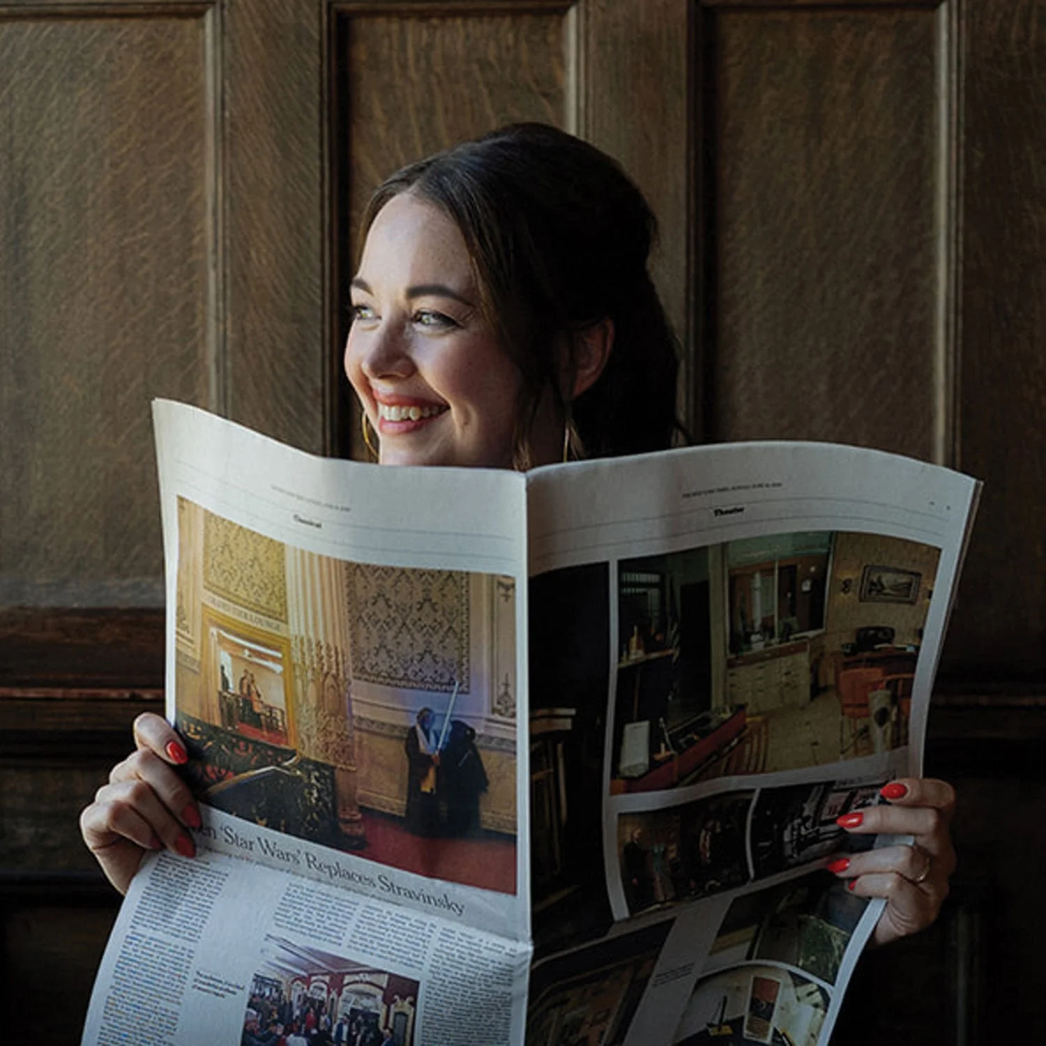 Jennifer Turner smiling and holding a vintage newspaper from her Gemini Copy Co brand photoshoot