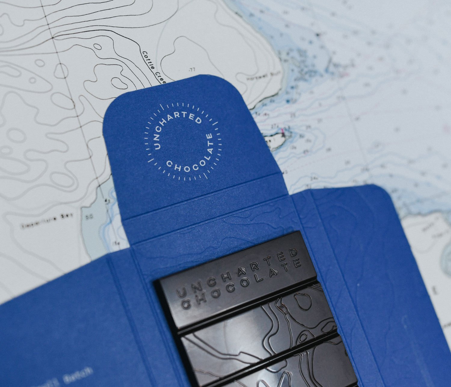 Chocolate packaging featuring a nautical design aesthetic and a compass-inspired logo design.