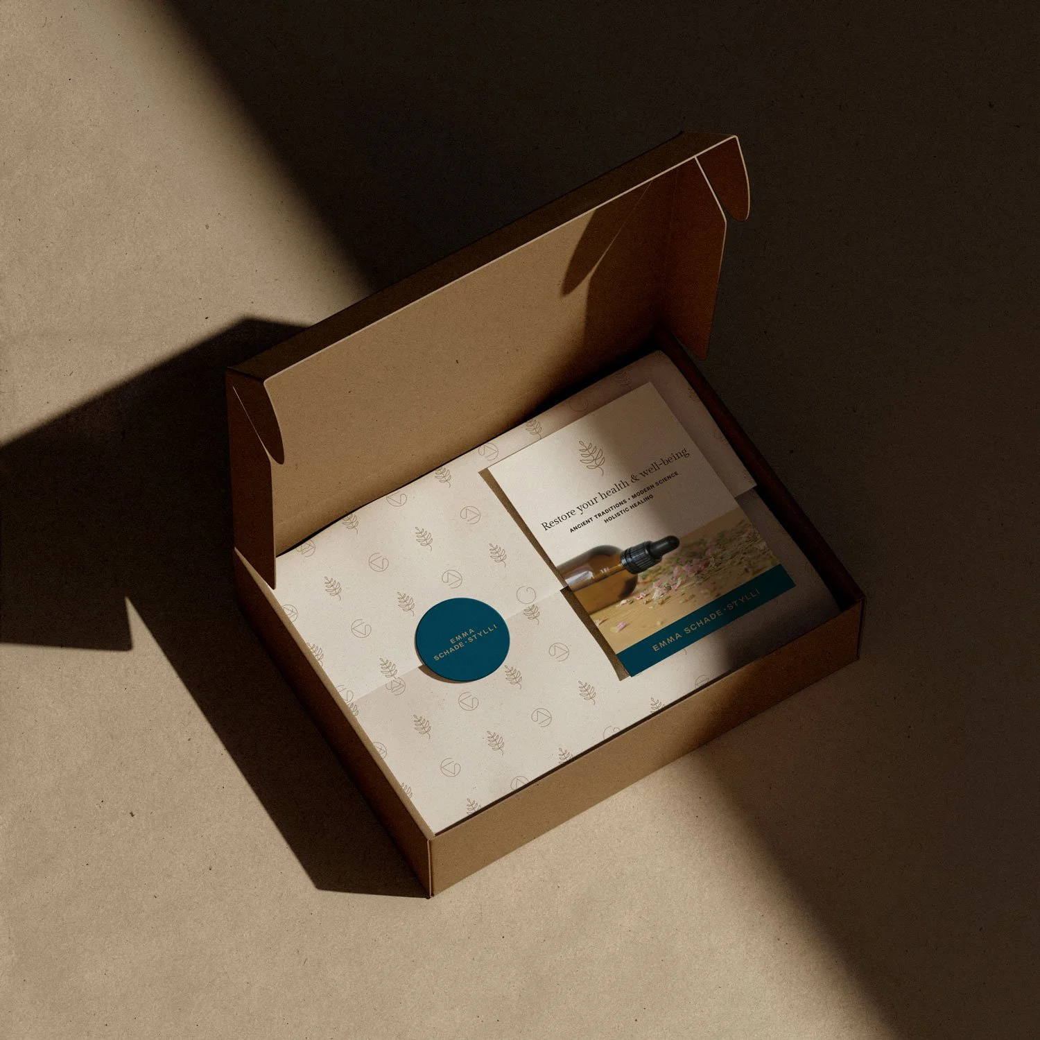Custom Emma Schade-Stylli brand packaging with tissue paper, sticker, and postcard inside a kraft mailer box