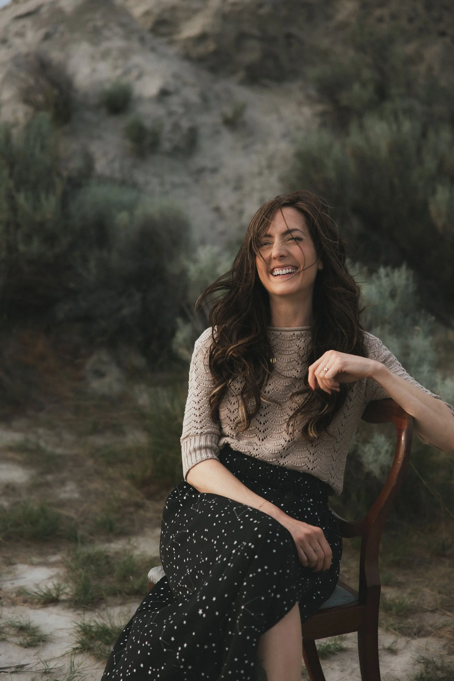 Miranda Braithwaite, Okanagan branding expert and founder of Moonstone Creative, laughing outdoors in a constellation skirt among desert sage