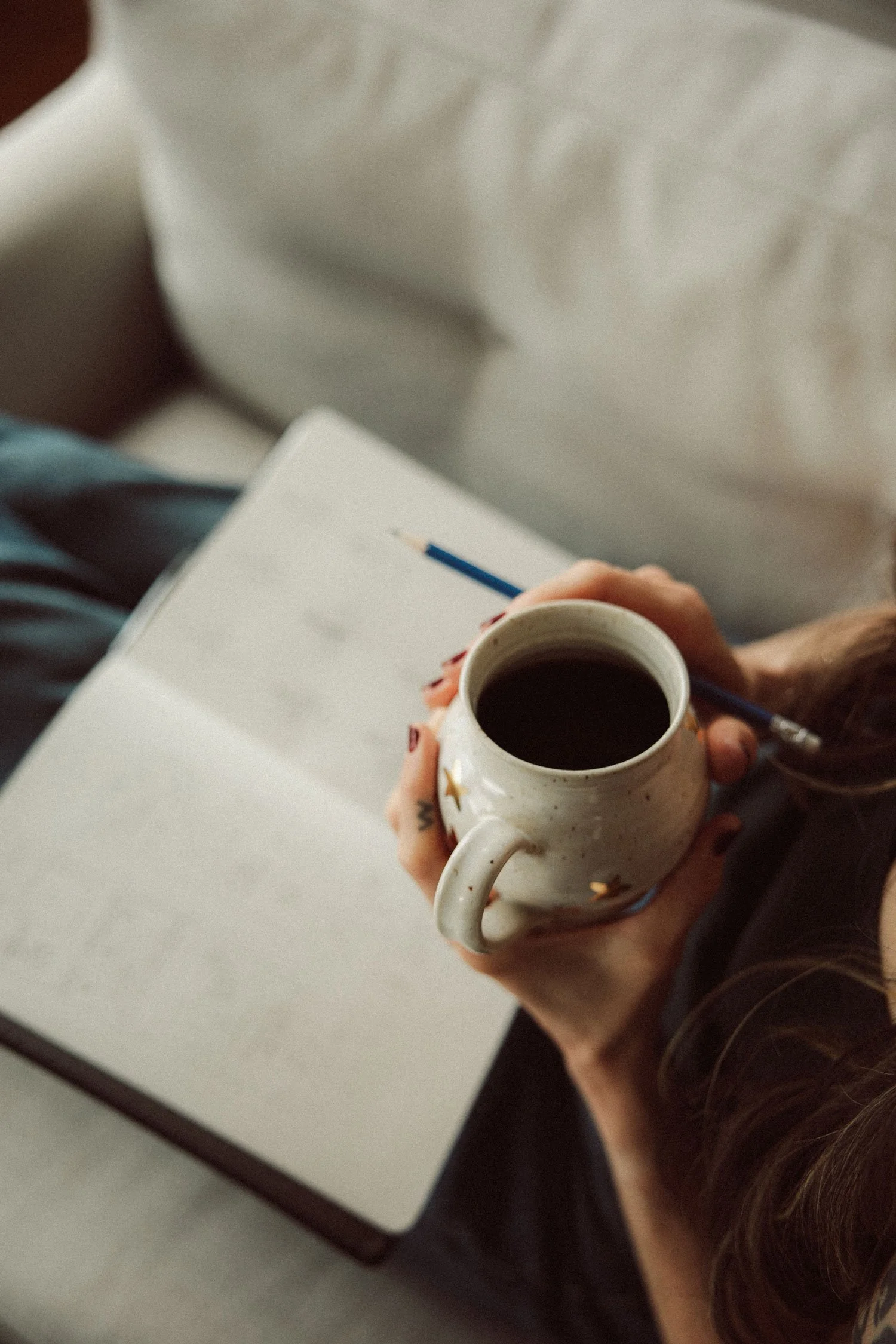 Miranda of Moonstone Creative holding a coffee mug and pencil over a sketchbook, planning a custom web design services project