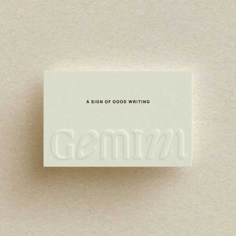 Gemini Copy Co's typographic logo, blind embossed on on cream, textured business cards with the tagline, "A sign of good writing"