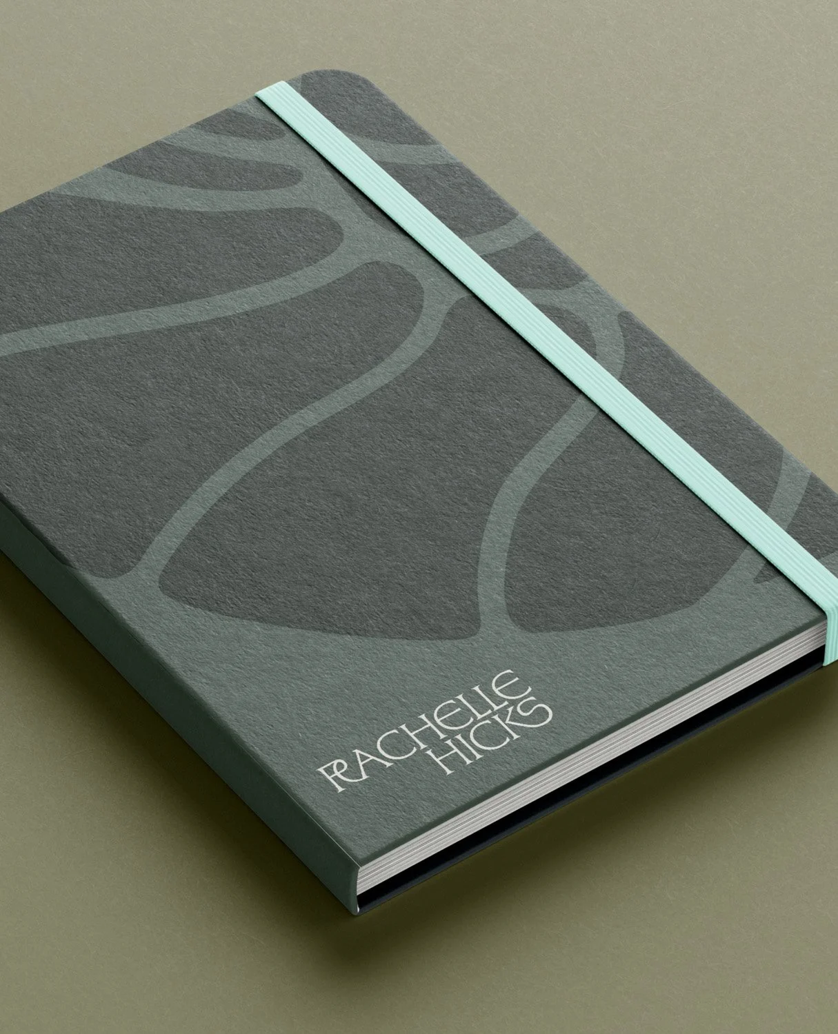 Rachelle Hicks Astrology branded notebook mockup in slate grey with organic pattern and mint elastic band designed by Moonstone Creative