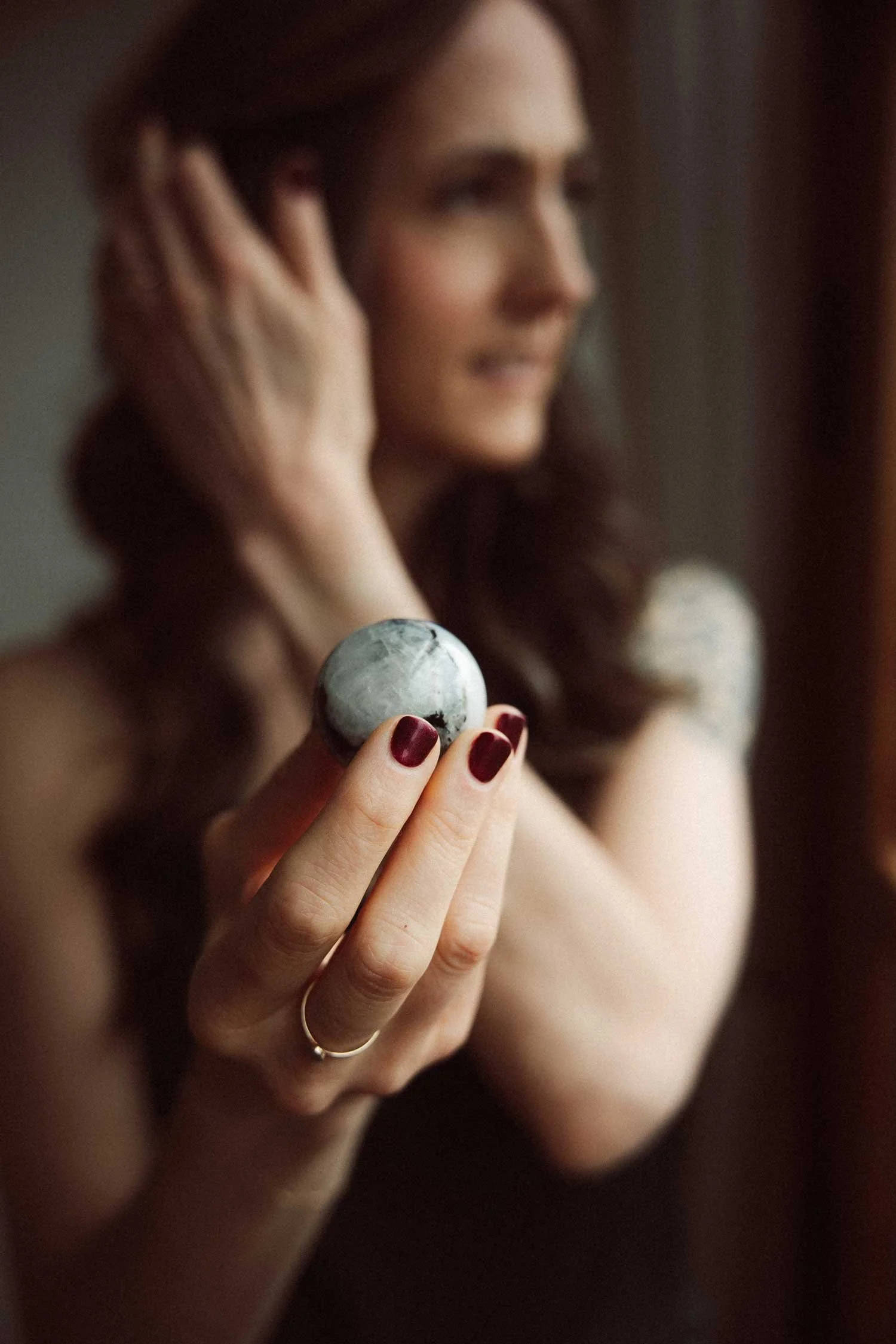 Miranda Braithwaite, founder of Moonstone Creative, holding a polished moonstone in soft focus