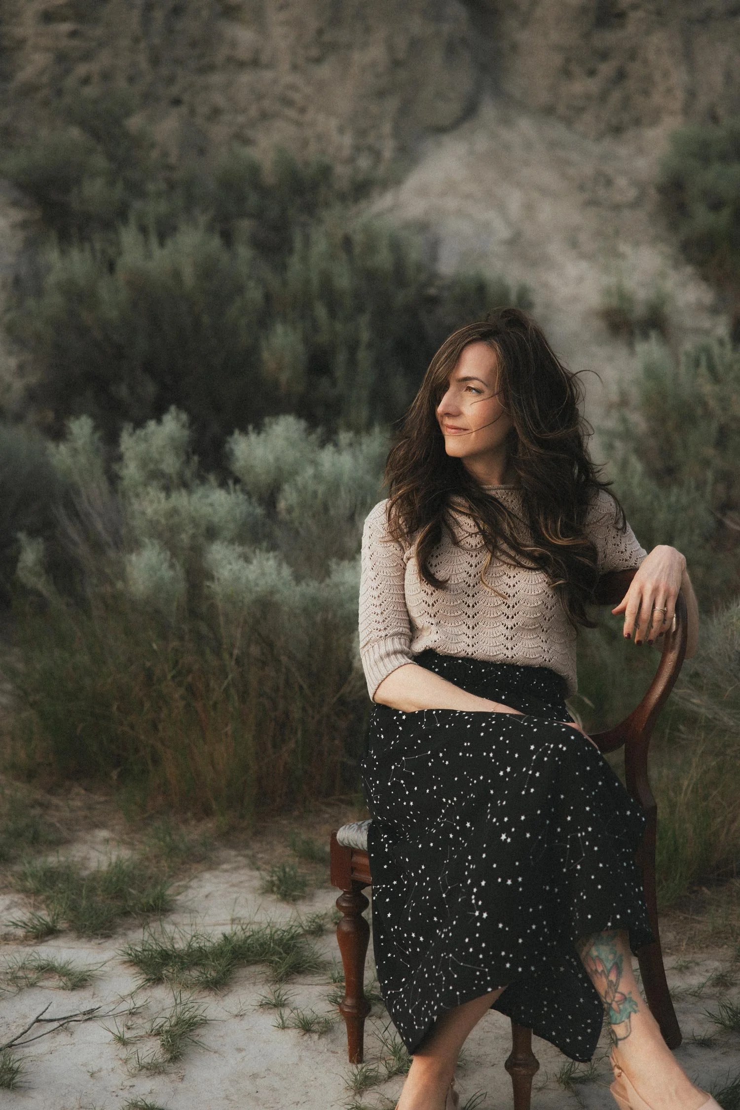Miranda Braithwaite, Okanagan brand designer and founder of Moonstone Creative, seated outdoors in a constellation skirt among desert sage