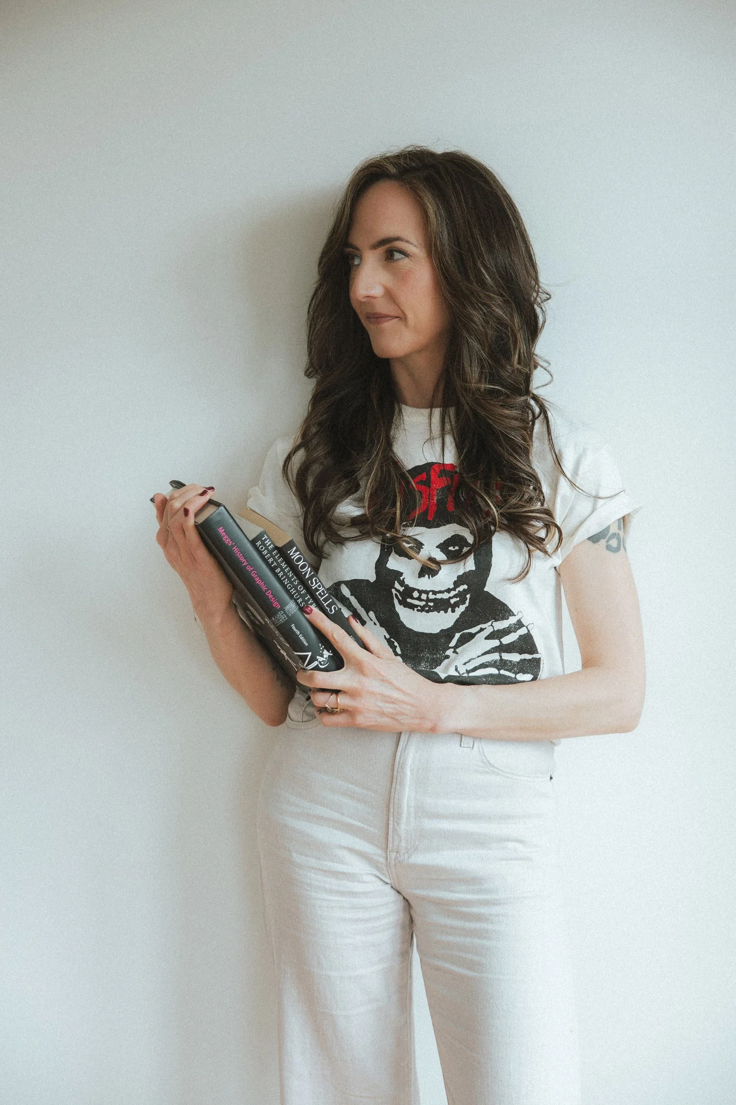 Moonstone Creative founder, Miranda Braithwaite, holding a stack of design and astrology books