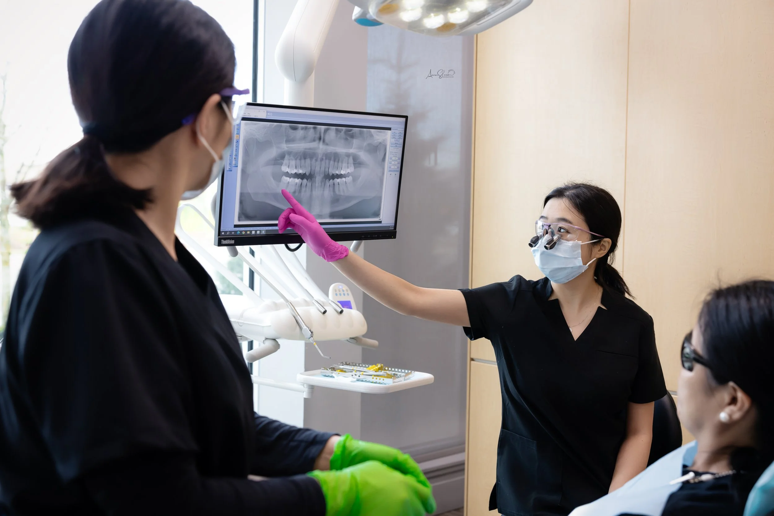 Dental professionals discussing a panoramic dental X-ray in a clinic exam room.